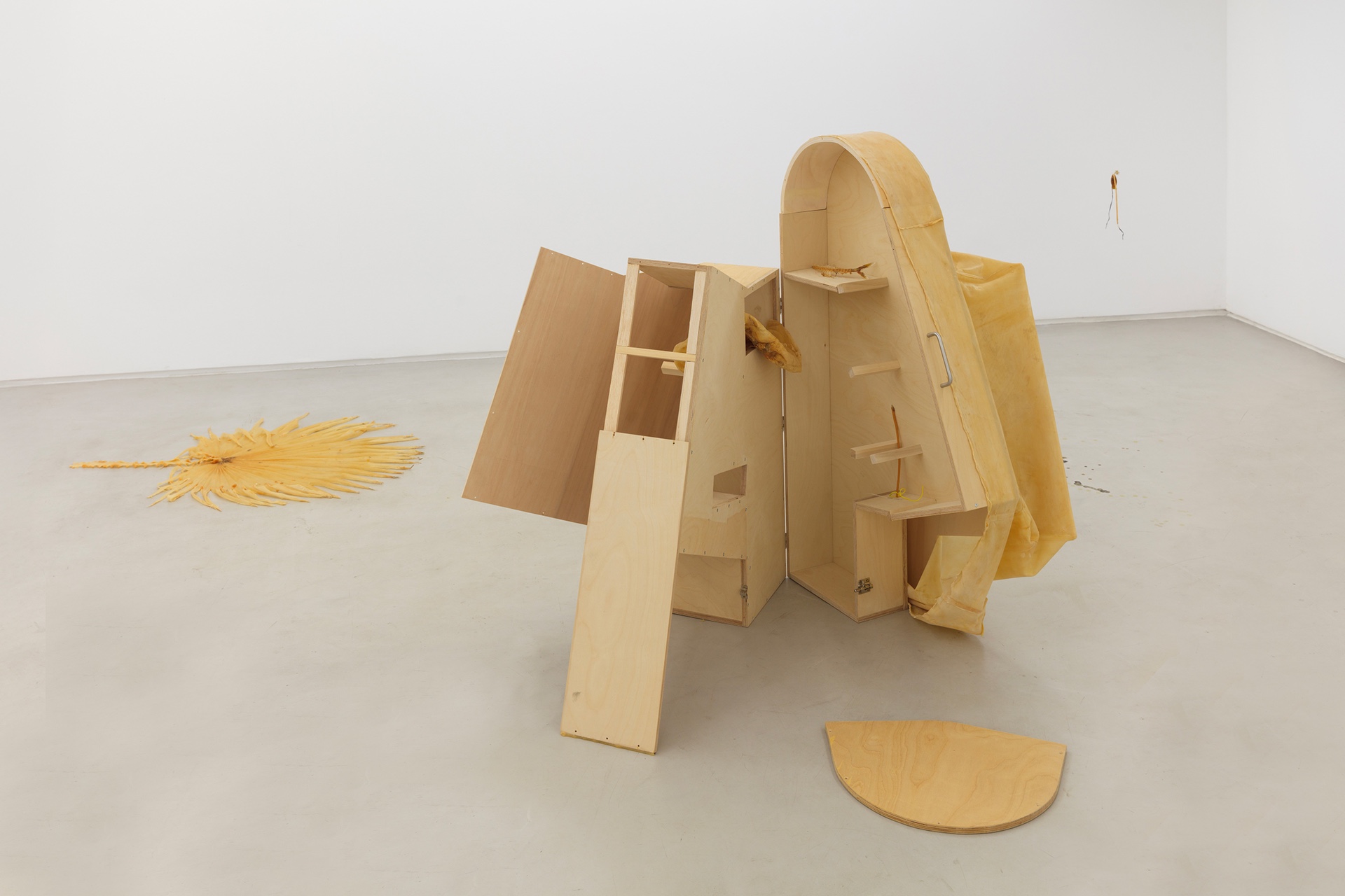 Não Faz Mal by Manon Harnois at Galeria Foco — A wooden sculptural structure dominates the gallery floor, constructed from pine and plywood in natural light tones.