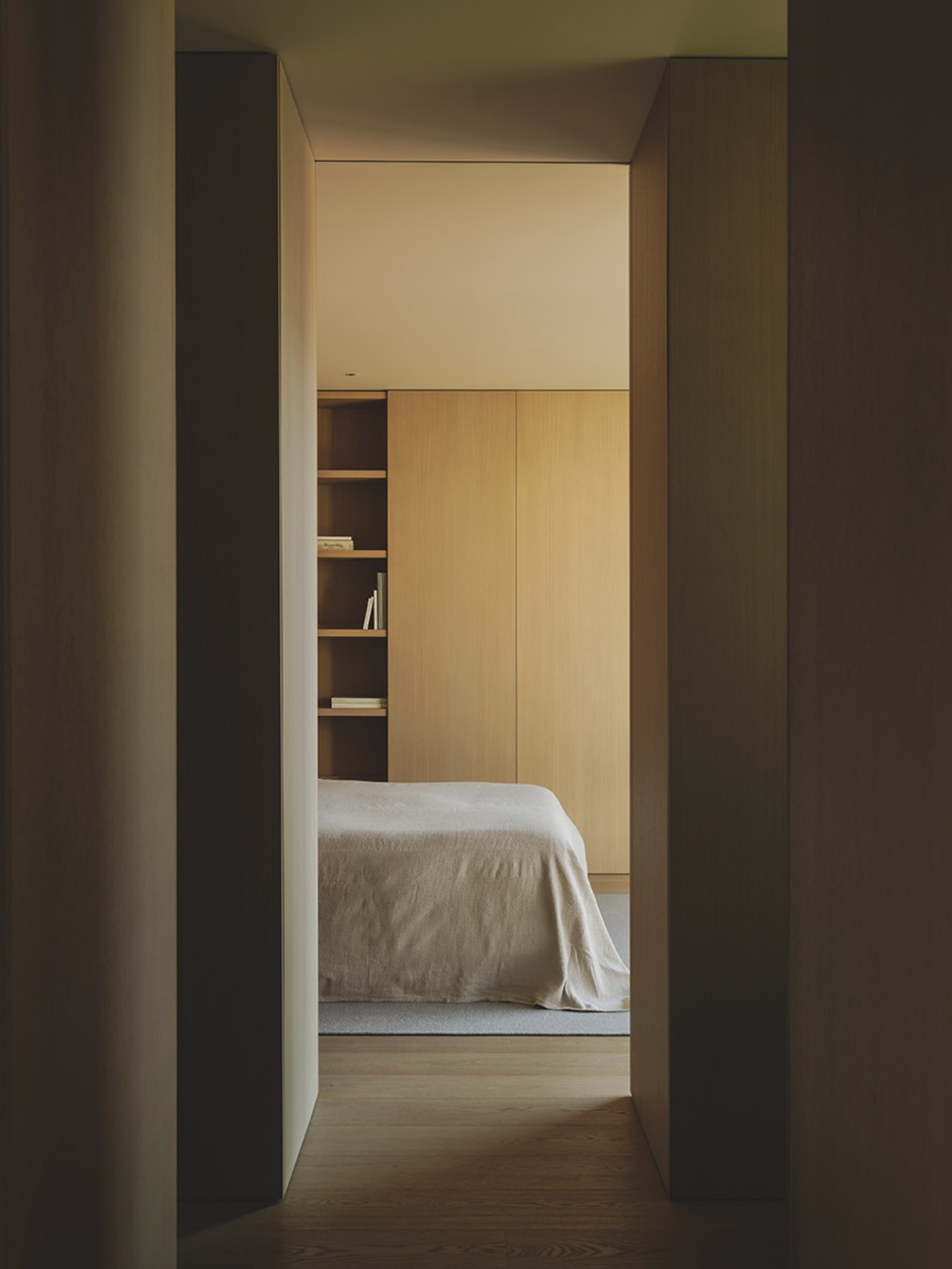 S29 House by Francesc Rifé Studio + Exit Projectes — A view through a narrow passage with dark-stained timber door frames opening onto a bedroom.
