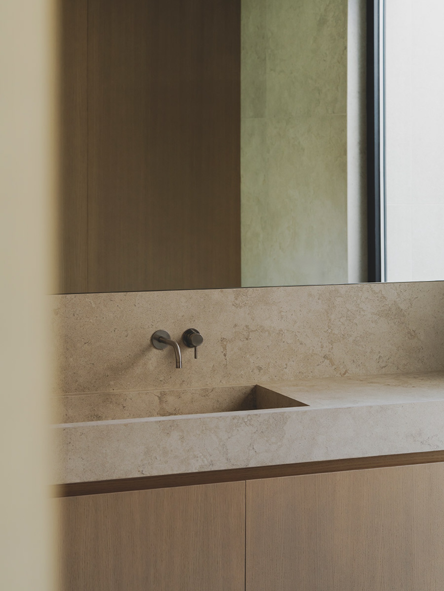 S29 House by Francesc Rifé Studio + Exit Projectes — Detail of a custom sink installation featuring a continuous travertine countertop with an integrated rectangular basin carved directly into the stone surface.