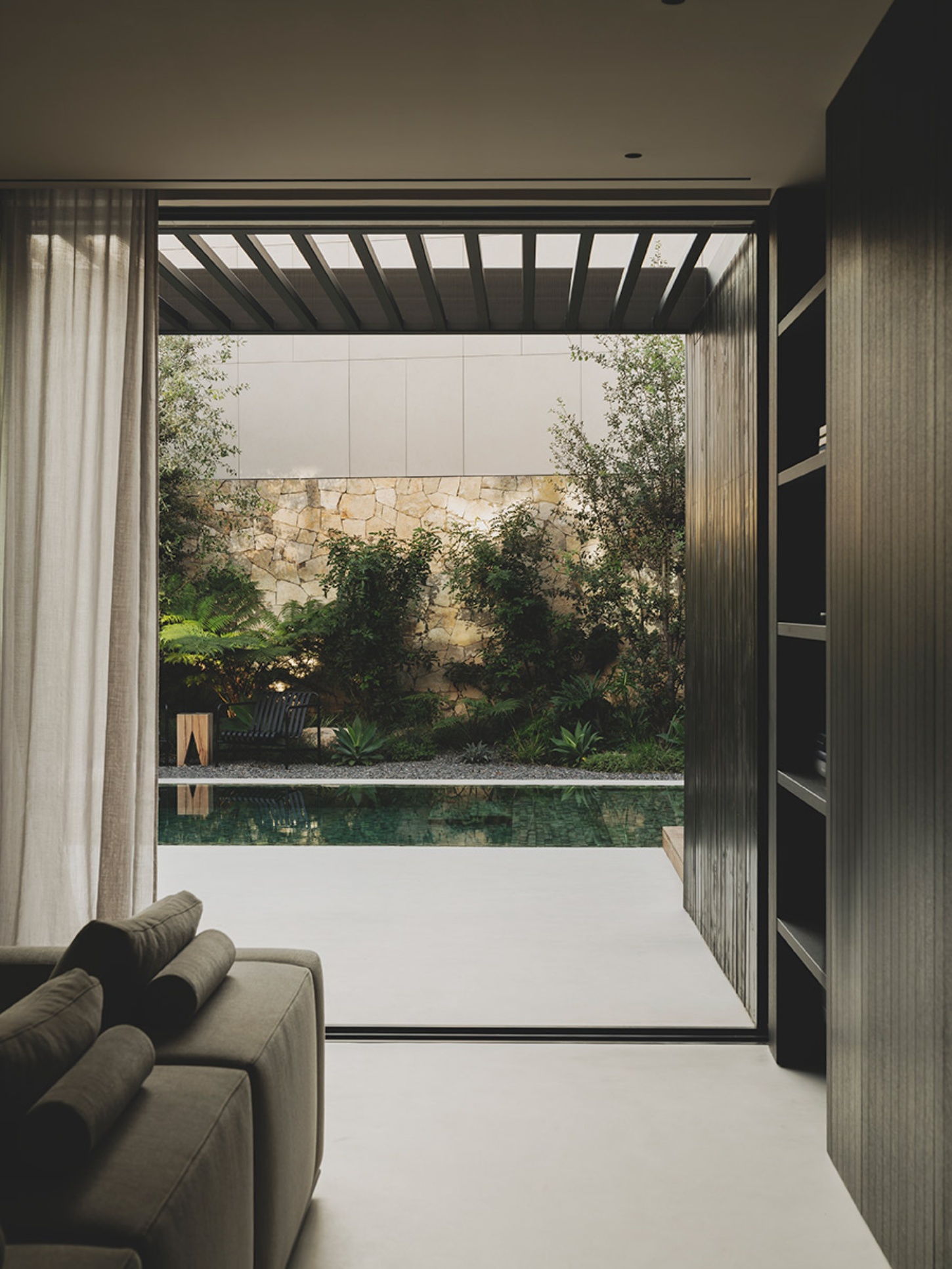 S29 House by Francesc Rifé Studio + Exit Projectes — A view through floor-to-ceiling glazed doors from an interior living space toward a contained garden courtyard.