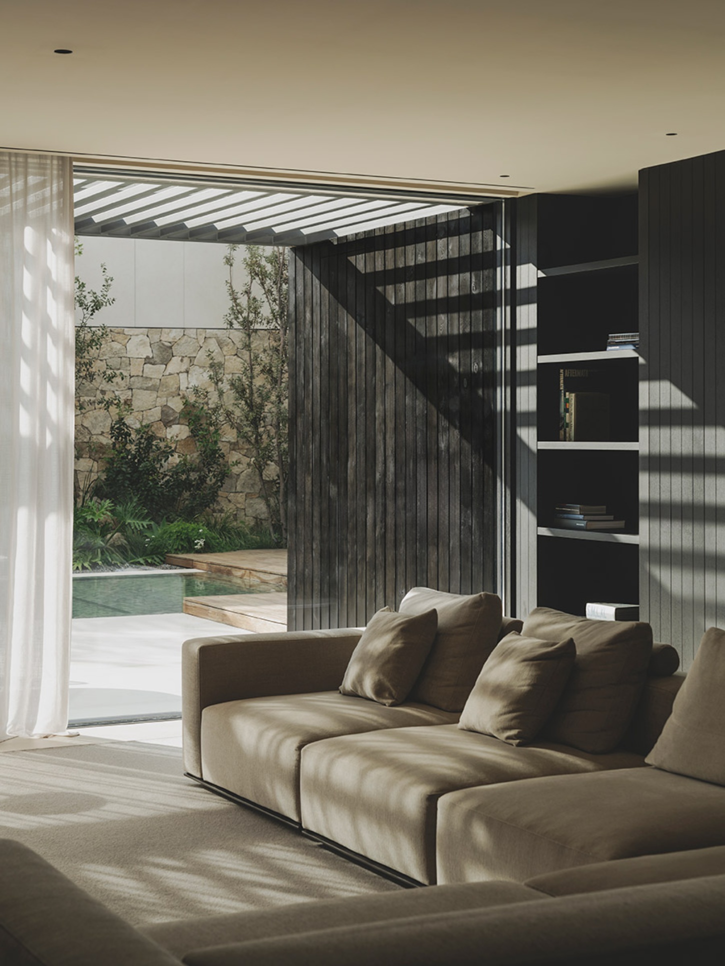 S29 House by Francesc Rifé Studio + Exit Projectes — A sectional sofa in cream linen anchors the living space, positioned to face the open threshold toward the courtyard.