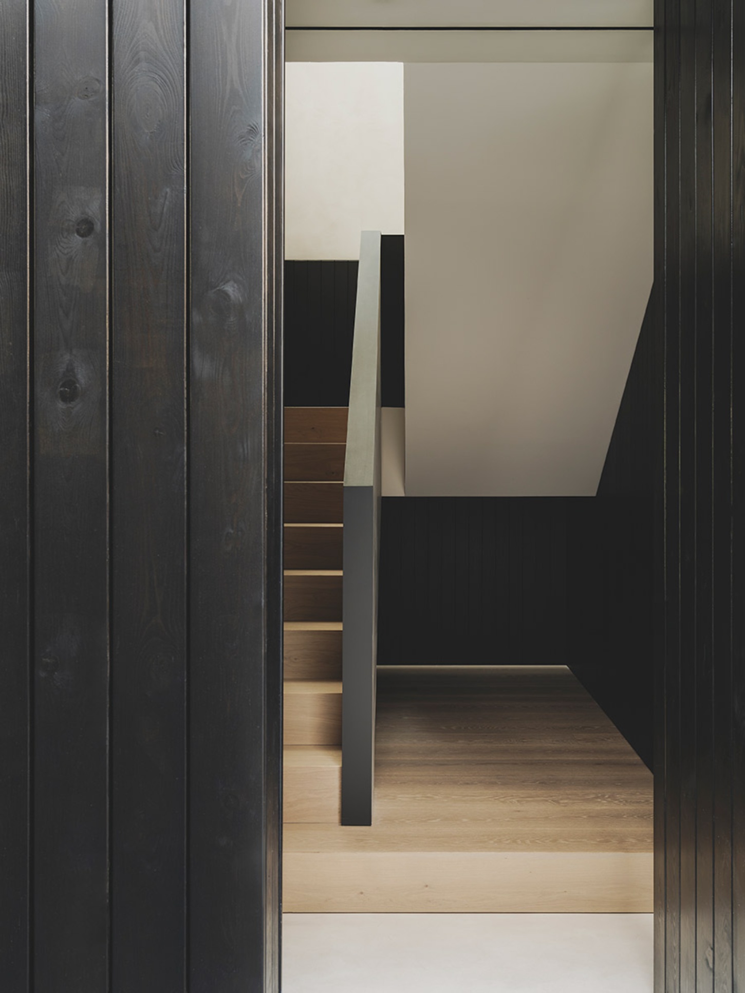 S29 House by Francesc Rifé Studio + Exit Projectes — A dark-stained timber passage frames the view into an adjacent gallery space.