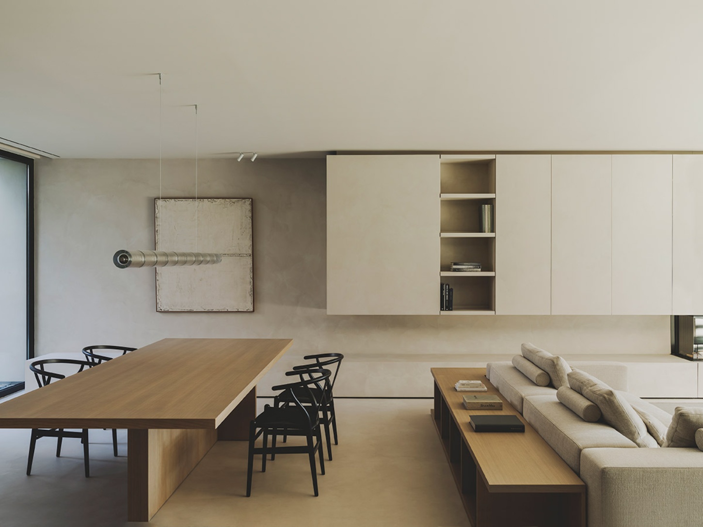 S29 House by Francesc Rifé Studio + Exit Projectes — A combined dining and living space demonstrates material restraint through a palette of cream, natural wood, and black accents.