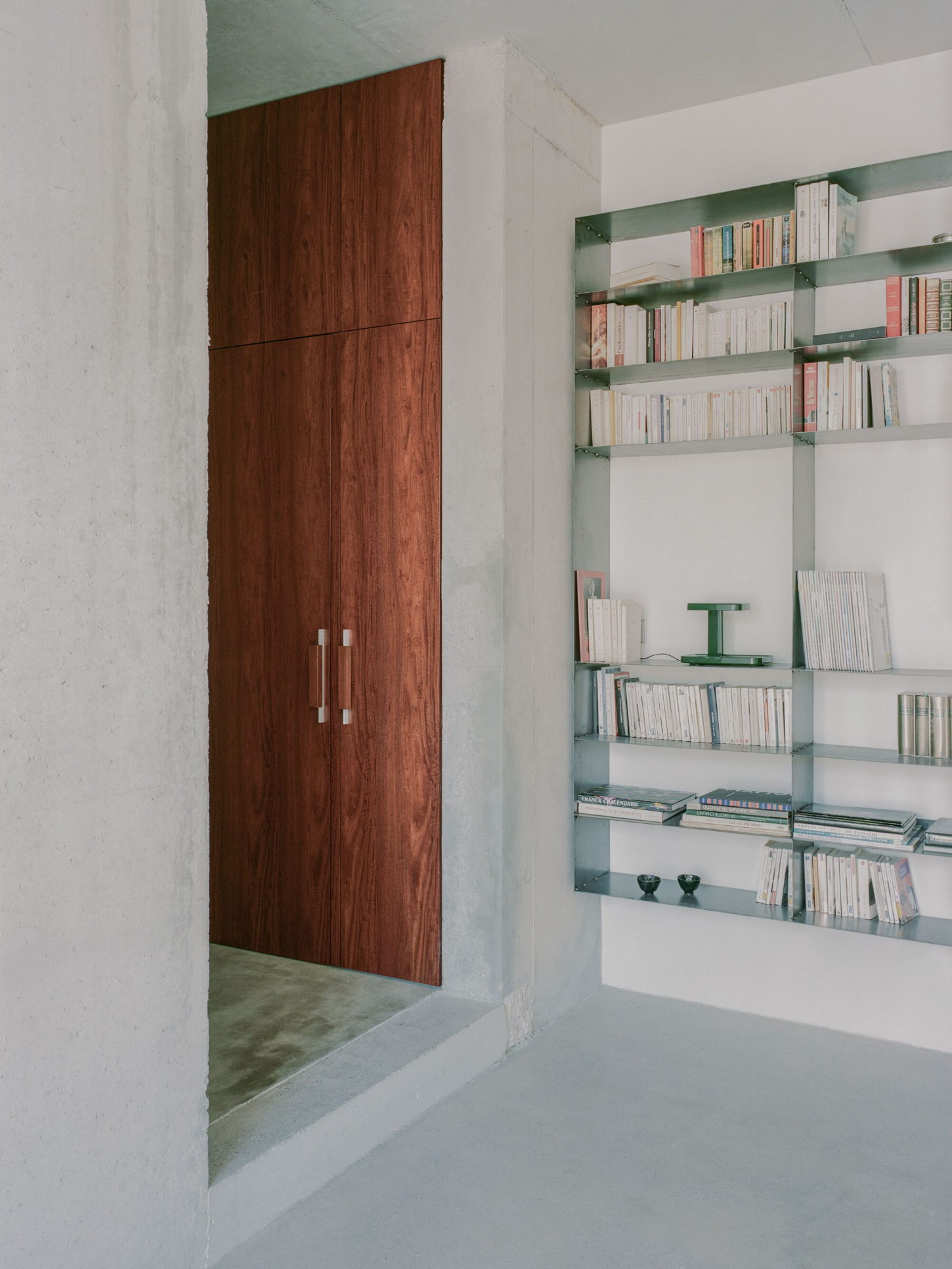 PAYZ House by Alors Studio — A passage framed by a monolithic timber door in deep burgundy-stained wood, fitted with minimalist steel handles.