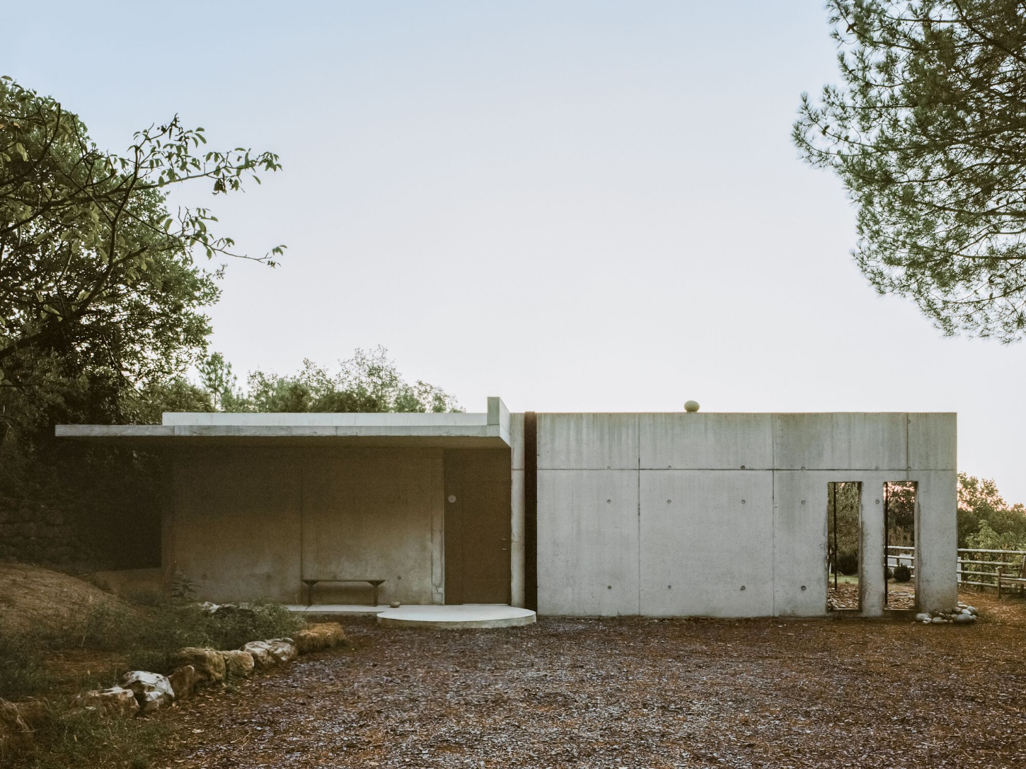 PAYZ House by Alors Studio — The PAYZ House presents its monolithic concrete volume across a gravel courtyard, bordered by Mediterranean vegetation.