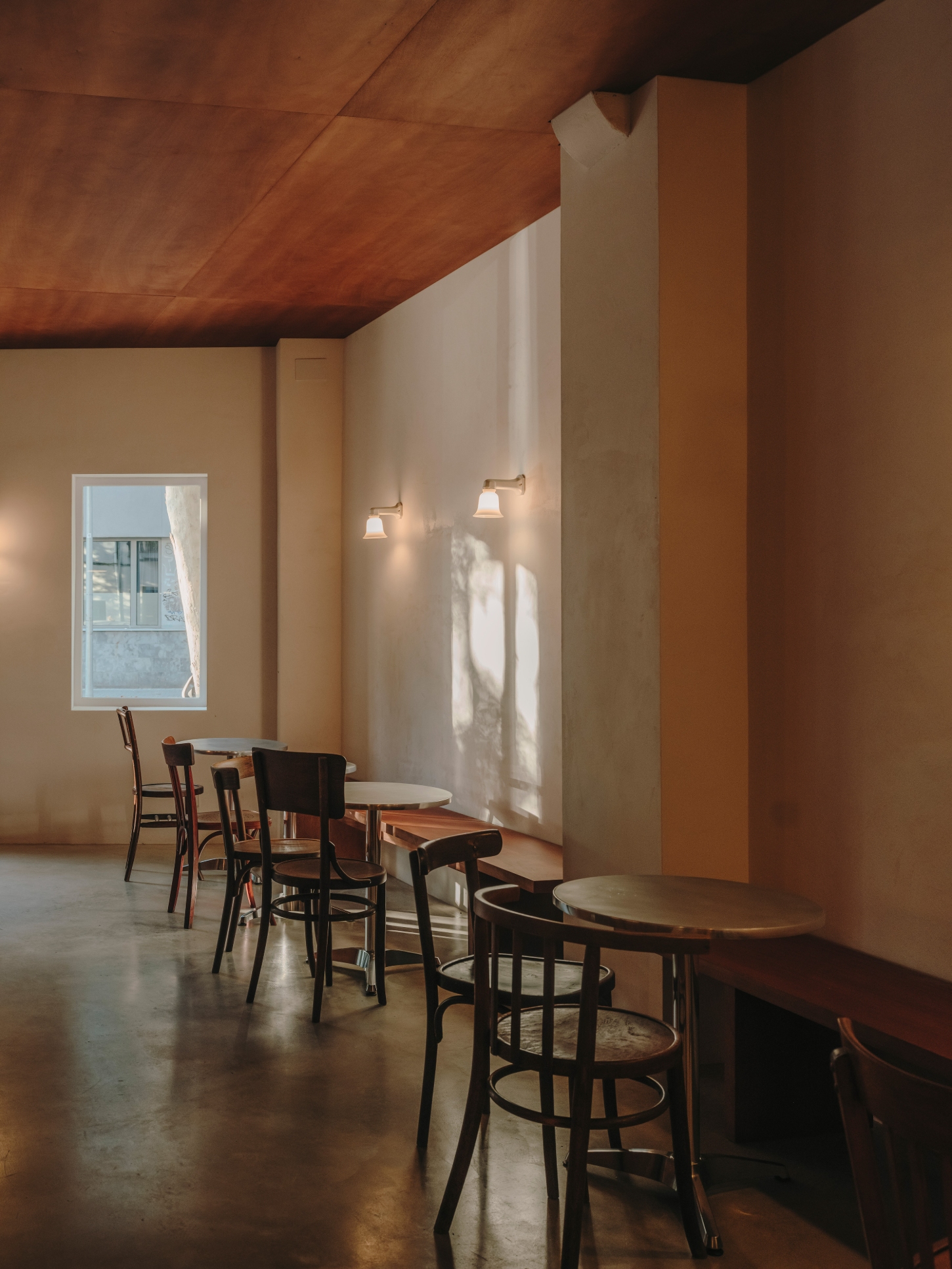 Nomad Coffee Frutas Selectas by Skye Maunsell and Jordi Veciana — The dining zone captures a moment of natural light across lime mortar walls, with bentwood café chairs arranged at small tables.