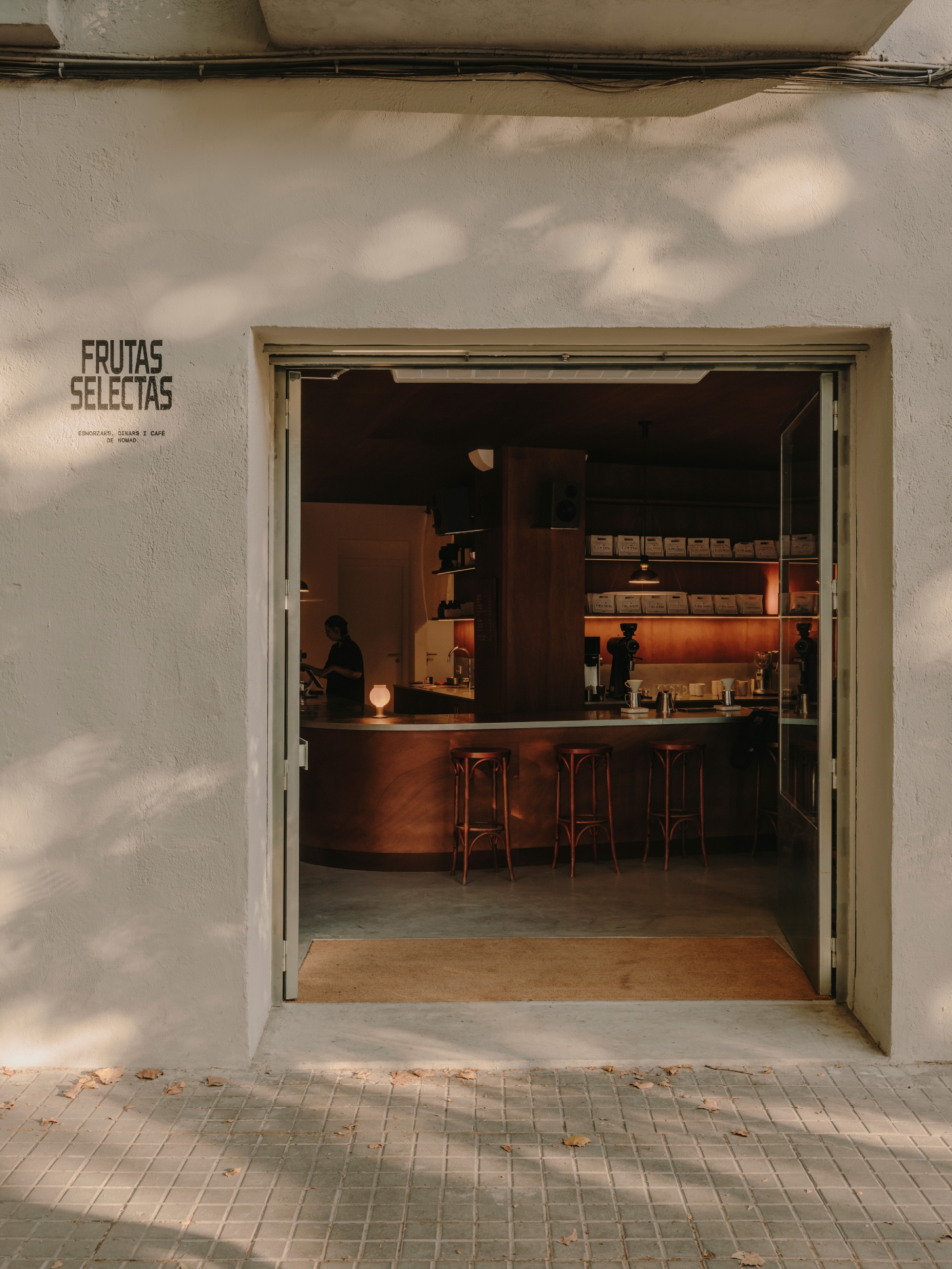 Nomad Coffee Frutas Selectas by Skye Maunsell and Jordi Veciana — The storefront elevation presents a recessed entrance framing the interior café.
