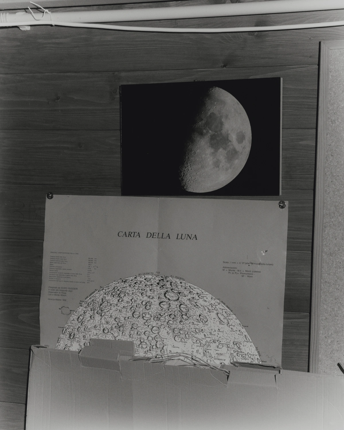 Protege Noctem by Mattia Balsamini & Raffaele Panizza — A black-and-white archival photograph documenting lunar cartography materials mounted on wooden paneling.