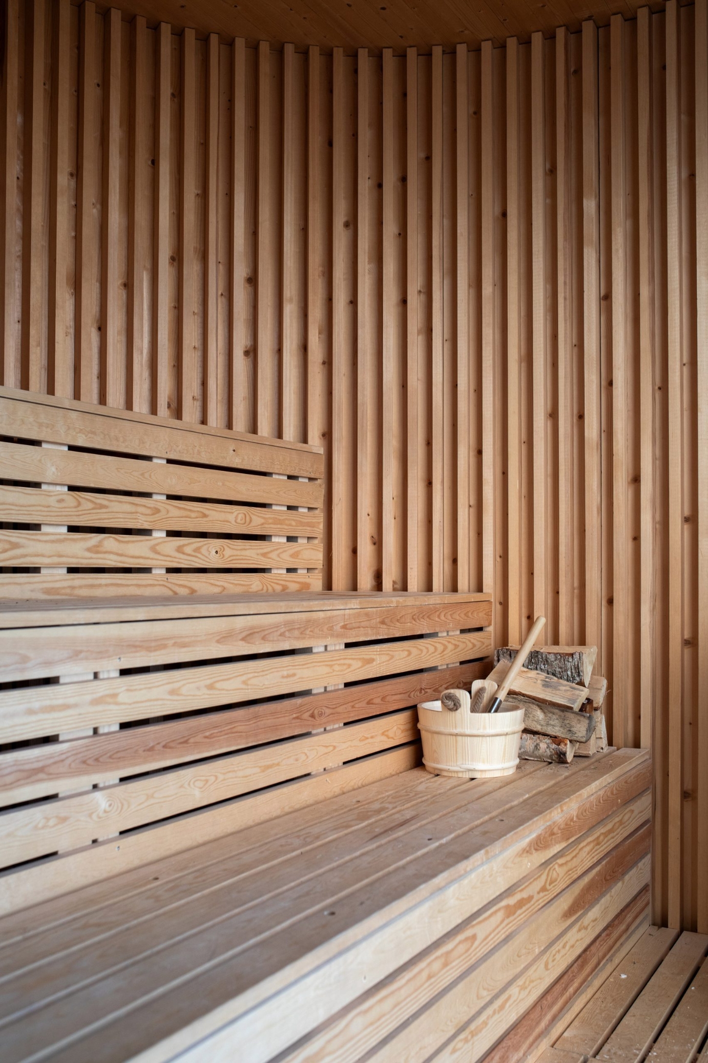 The Hotspot Oslo Works — Interior view of the sauna's bench seating, constructed from horizontal wooden slats with black gaps creating rhythm across the tiered platform.