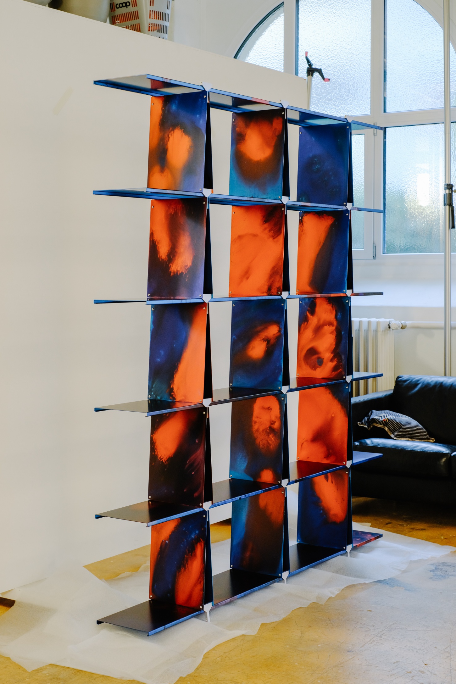 ‘Philae’ by Raphael Kadid — Philae presents a 3x3 grid of hand-anodized aluminum panels suspended between horizontal blue metal rods, creating a freestanding sculptural partition.