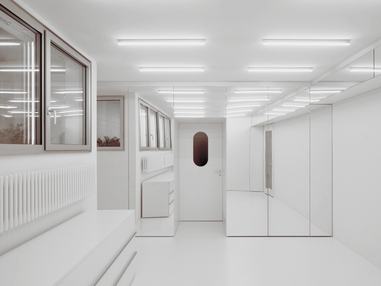1930’s House Zurich by Ductus by Ductus St — A corridor in white ceramic tile extends through the renovated 1930s house, its grid pattern establishing visual continuity across the floor.