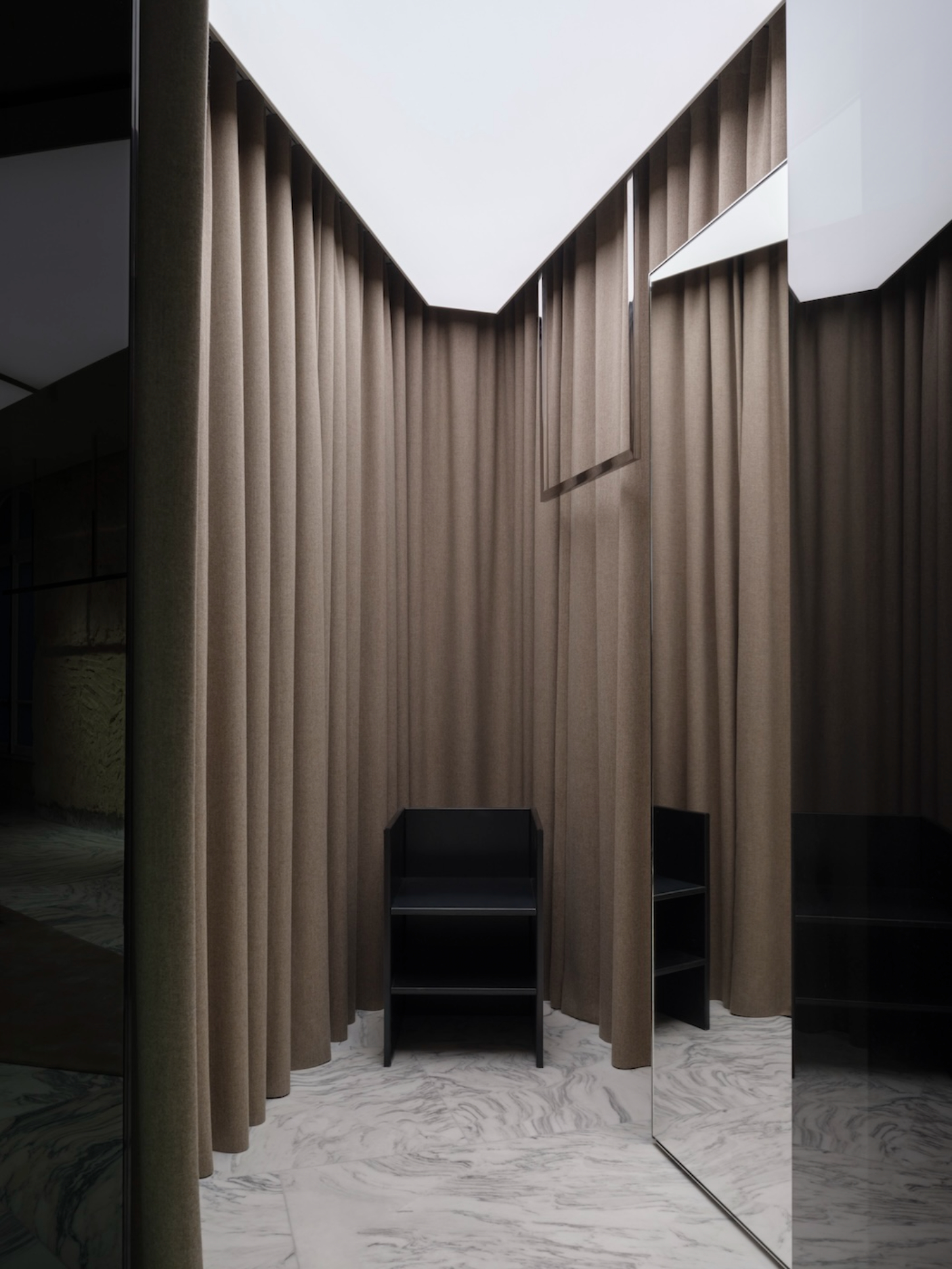 Saint Laurent Flagship in Paris by Sain Laurent — A dressing room enclosure defined by floor-to-ceiling linen curtains suspended from concealed rods, creating a U-shaped passage.
