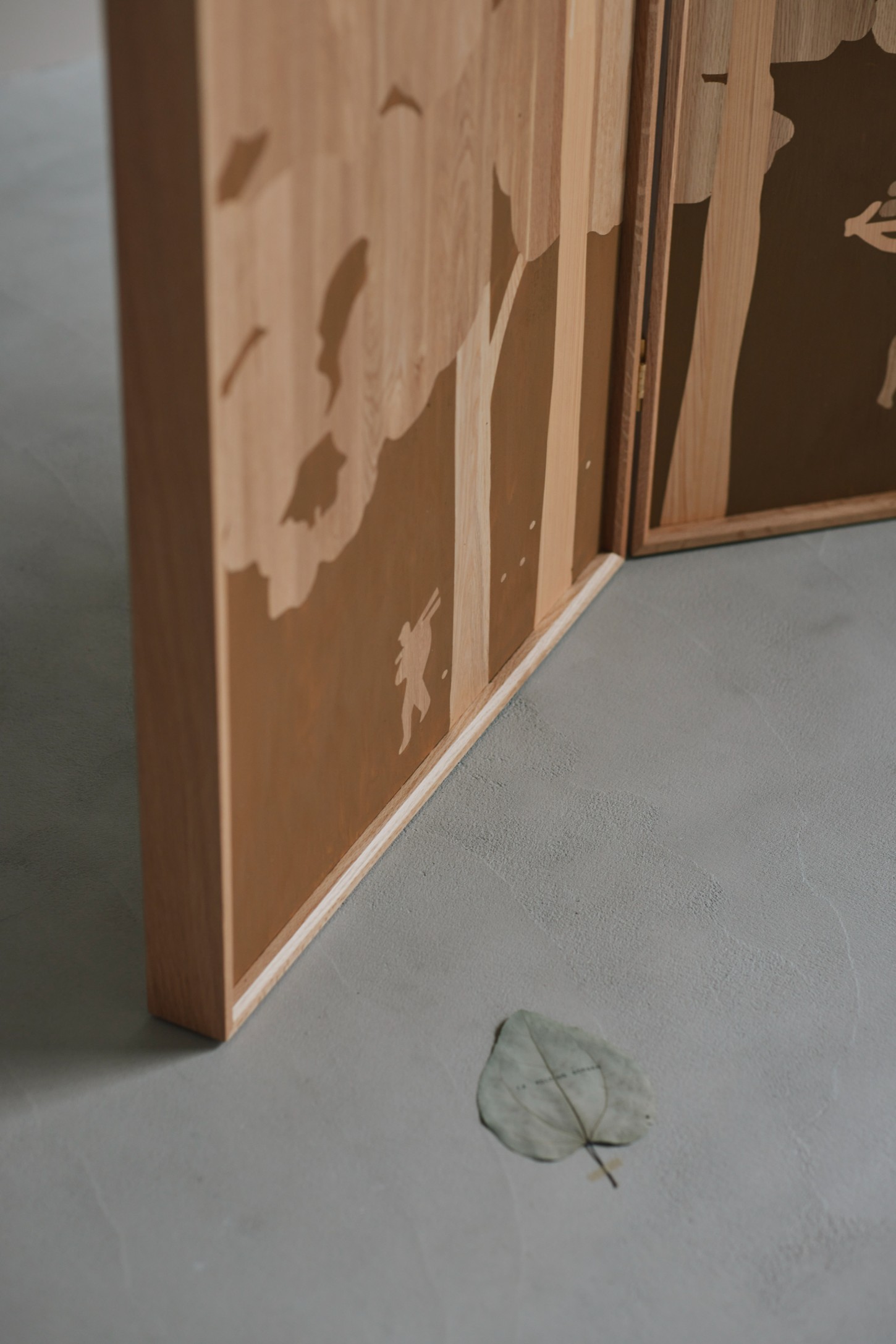 'The Age of Wood' by CHRISTIAN + JADE in Karimoku Research — Close-up view of the timber grid-wall structure from 'The Age of Wood' exhibition, showing the modular compartments with inlaid botanical silhouettes in...