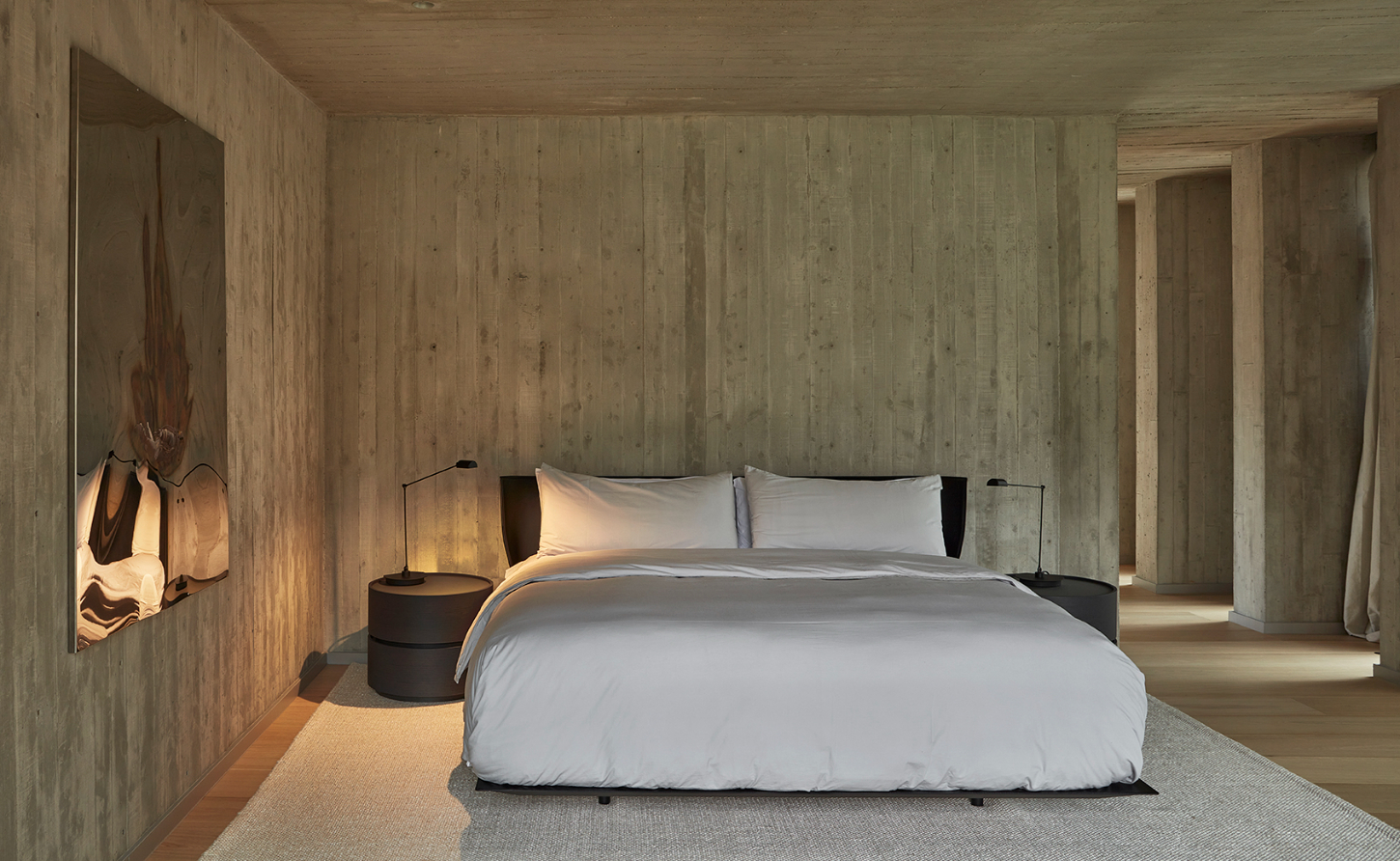 Casa Haras by 5Solidos — A bedroom volume defined by vertical concrete fluting that creates a rhythmic linear pattern across walls and ceiling.