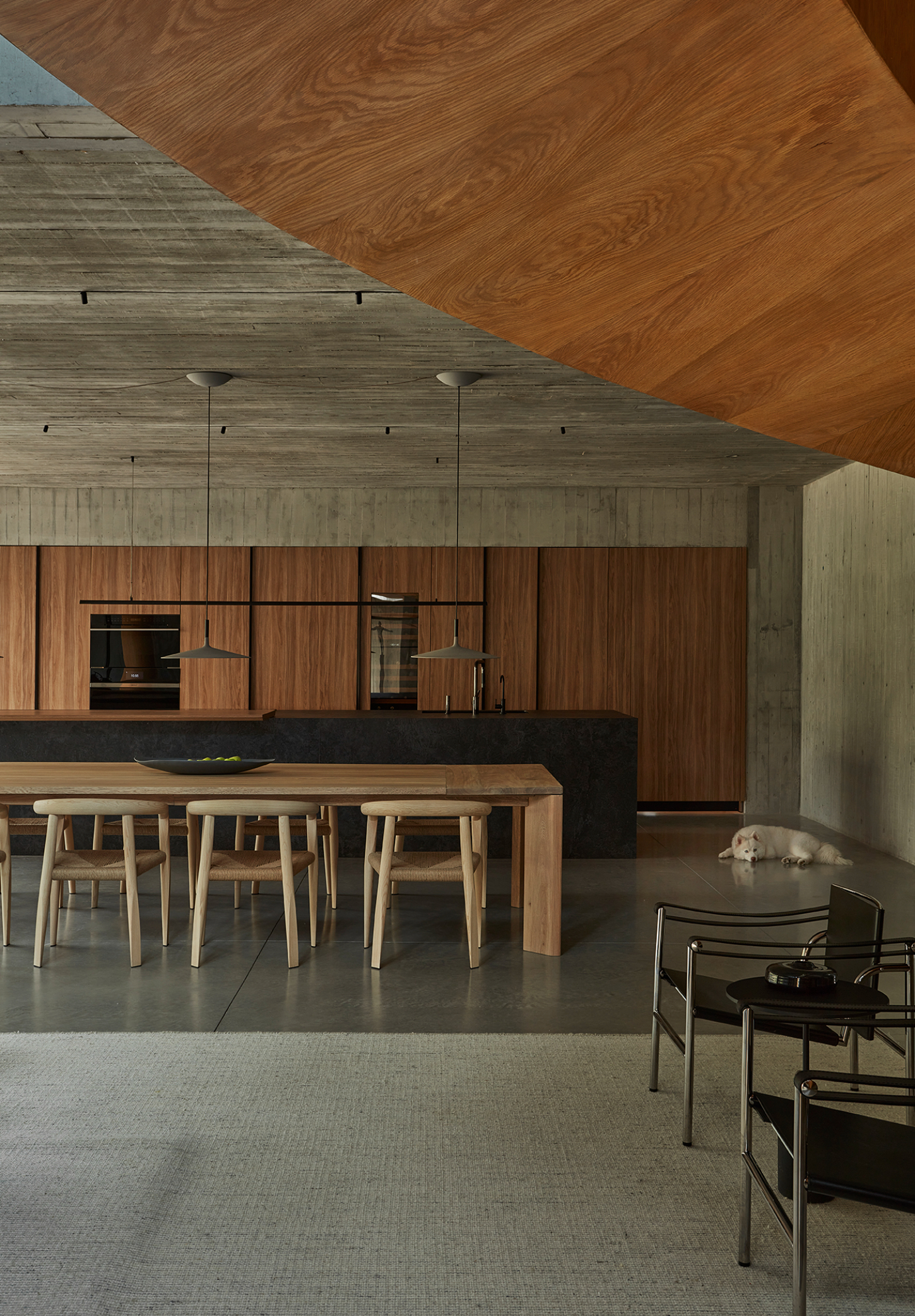 Casa Haras by 5Solidos — Casa Haras's open-plan kitchen and dining area demonstrates material hierarchy through contrasting wood tones and finishes.
