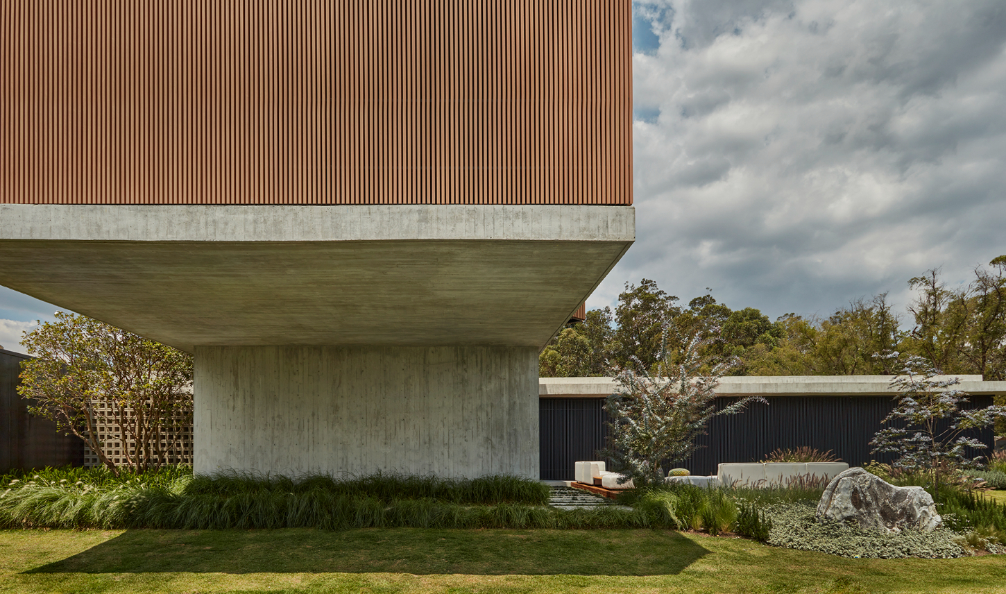 Casa Haras by 5Solidos — Casa Haras presents itself as a monolithic concrete form, its raw board-formed walls creating pronounced vertical fluting that anchors the composition.