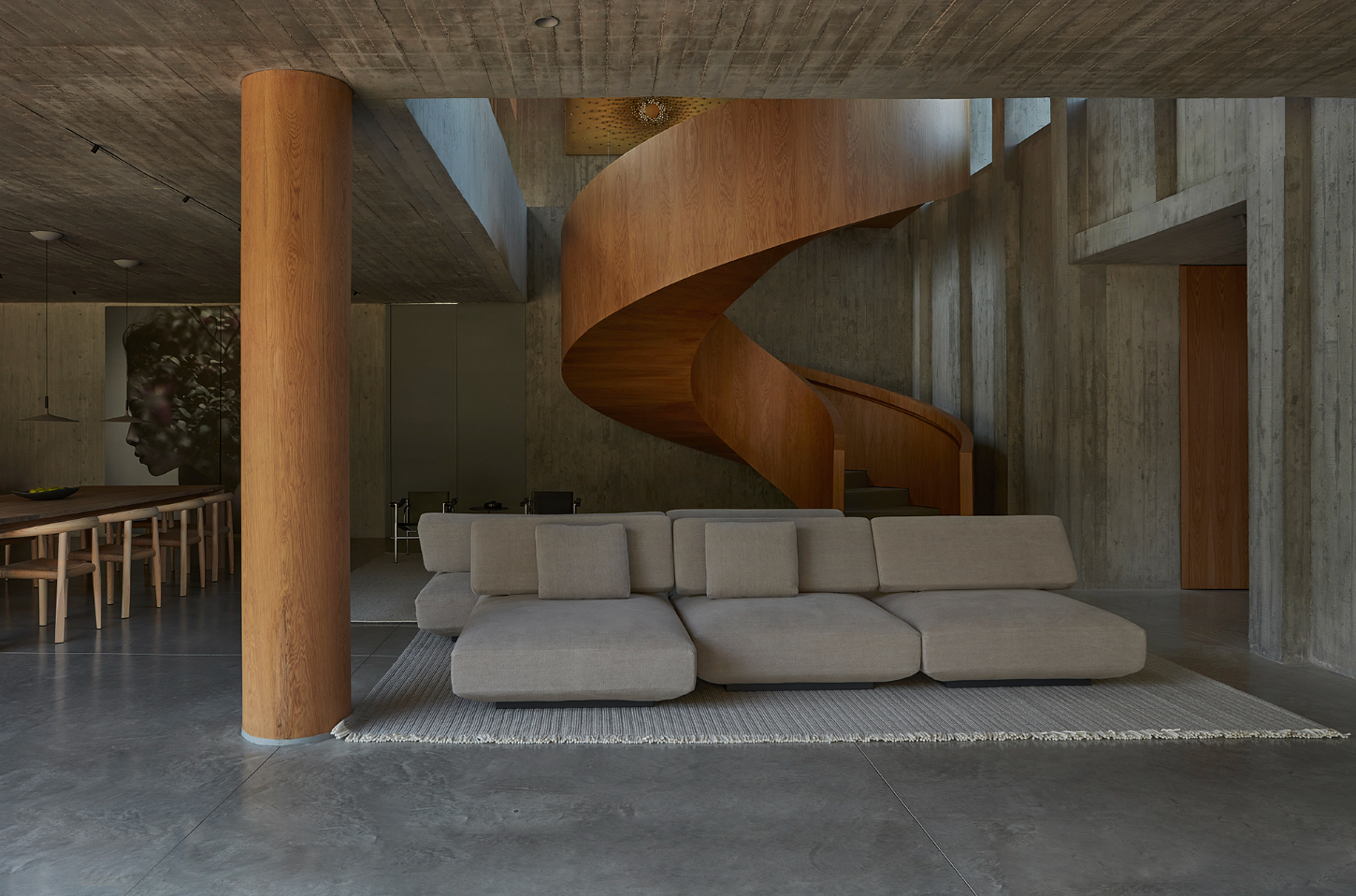 Casa Haras by 5Solidos — A double-height living space anchored by a sculptural helical timber staircase in warm oak, its continuous curved form dominating the composition.