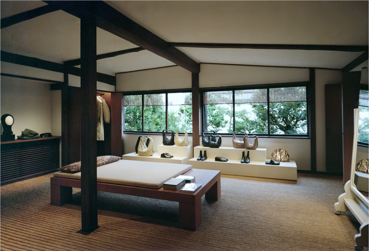 LEMAIRE Ebisu by Studio Hashimura by LEMAIRE by Studio Hashimura — A flagship retail interior organized around a central canopy bed structure with dark timber posts and cream upholstery.