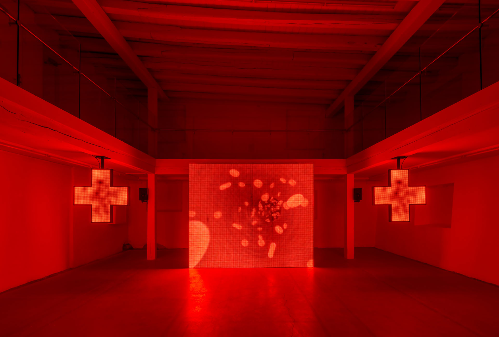 Milk Plus by Jens Settergren Viborg Kunsthal — A symmetrical gallery installation featuring two illuminated LED cross symbols flanking a central pixelated screen displaying abstract orange and red imagery.
