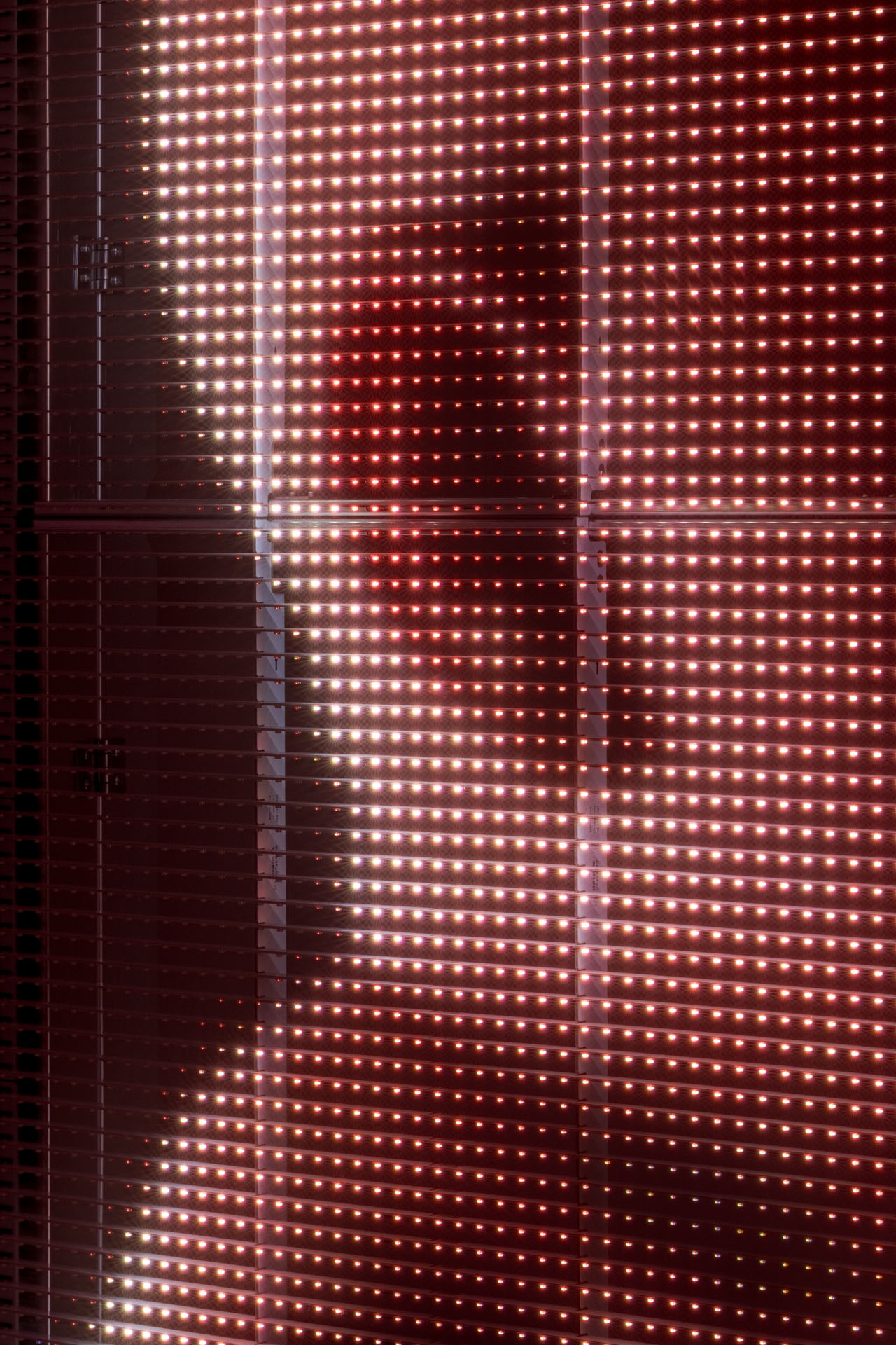 Milk Plus by Jens Settergren Viborg Kunsthal — A large-scale LED screen dominates the gallery interior, its low-resolution pixel grid emitting warm red and cream-colored light in a dense, uniform matrix.