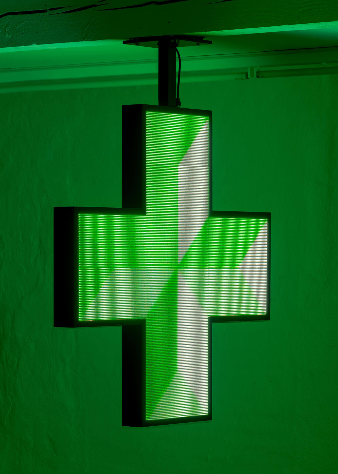 Milk Plus by Jens Settergren Viborg Kunsthal — A large-scale LED pixel display mounted on a black steel frame hangs from the gallery ceiling, suspended against a vibrant green-painted wall.