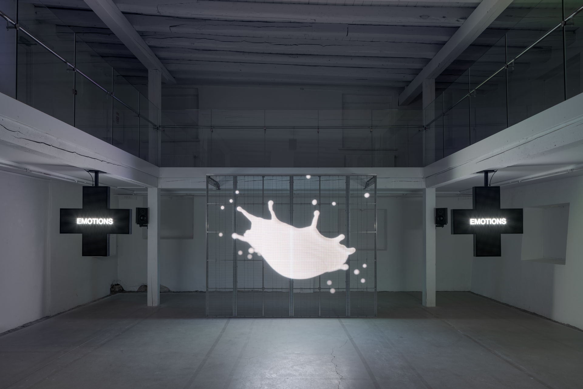Milk Plus by Jens Settergren Viborg Kunsthal — A video installation occupies the gallery's central axis, displaying a white milk splash rendered in low-resolution LED pixels against a dark grid-patterned...