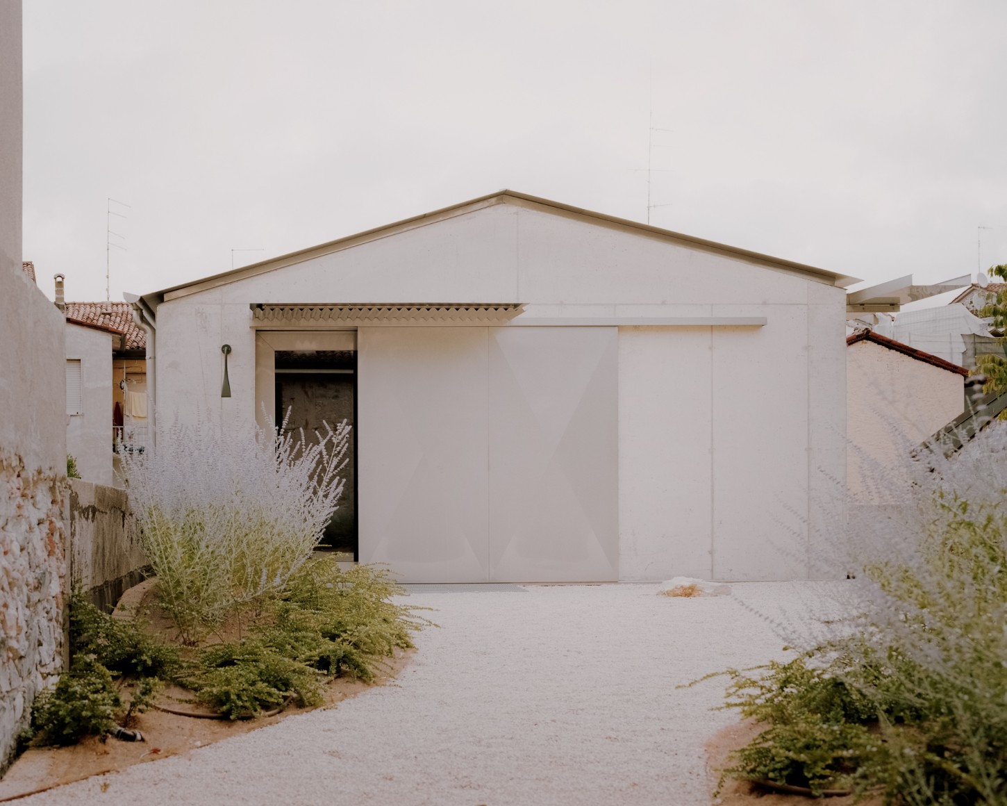 Atipografia Threshold and Treasure Gallery by AMAA — A board-formed concrete pavilion with a cantilevered roof slab frames the threshold between exterior and gallery space.