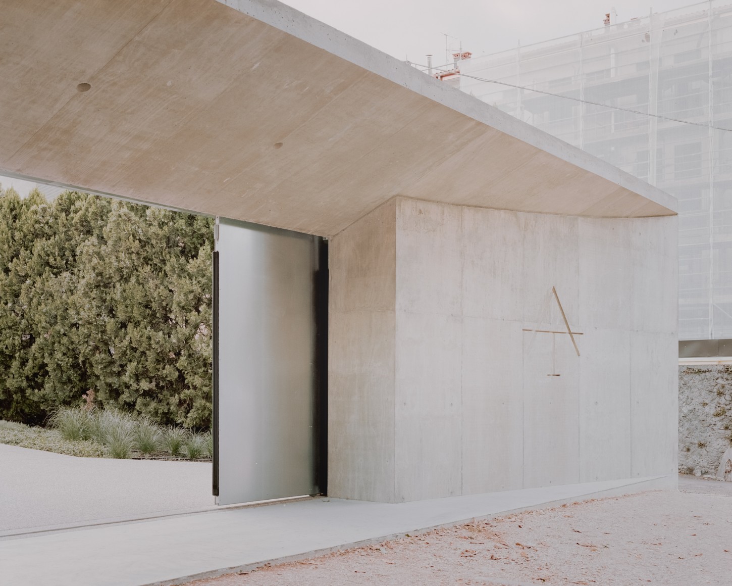 Atipografia Threshold and Treasure Gallery by AMAA — The threshold pavilion presents a monolithic concrete structure with board-formed casting marks visible across its surfaces.