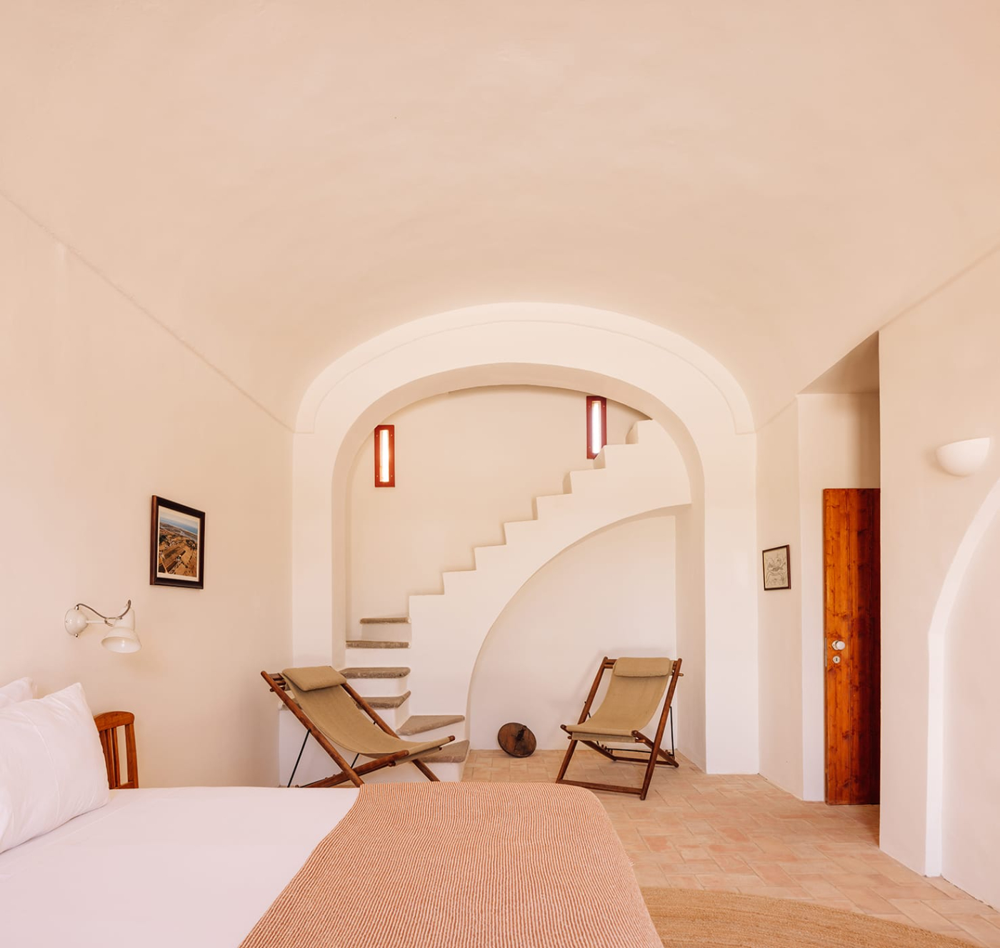 Quinta do Pinheiro by Frederico Valsassina — A guest room with whitewashed walls warmed to pale pink by Algarve light opens onto a sunken sitting area accessed by a sculptural arched passage.