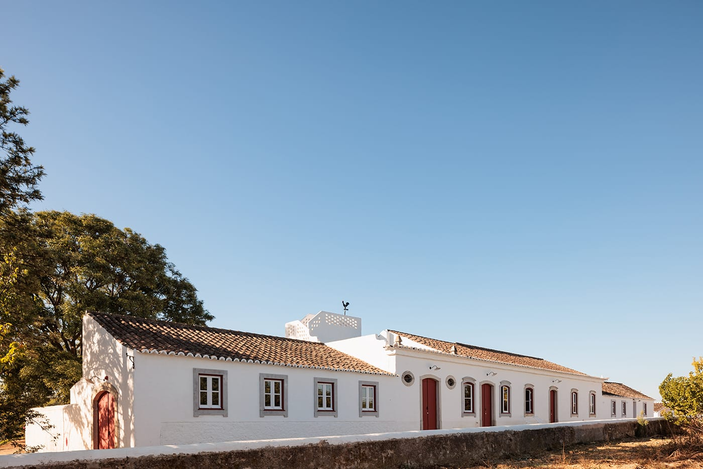 Quinta do Pinheiro by Frederico Valsassina — The whitewashed rendered facade of Quinta do Pinheiro presents a linear composition of repetitive fenestration, with paired timber-framed windows rendered...