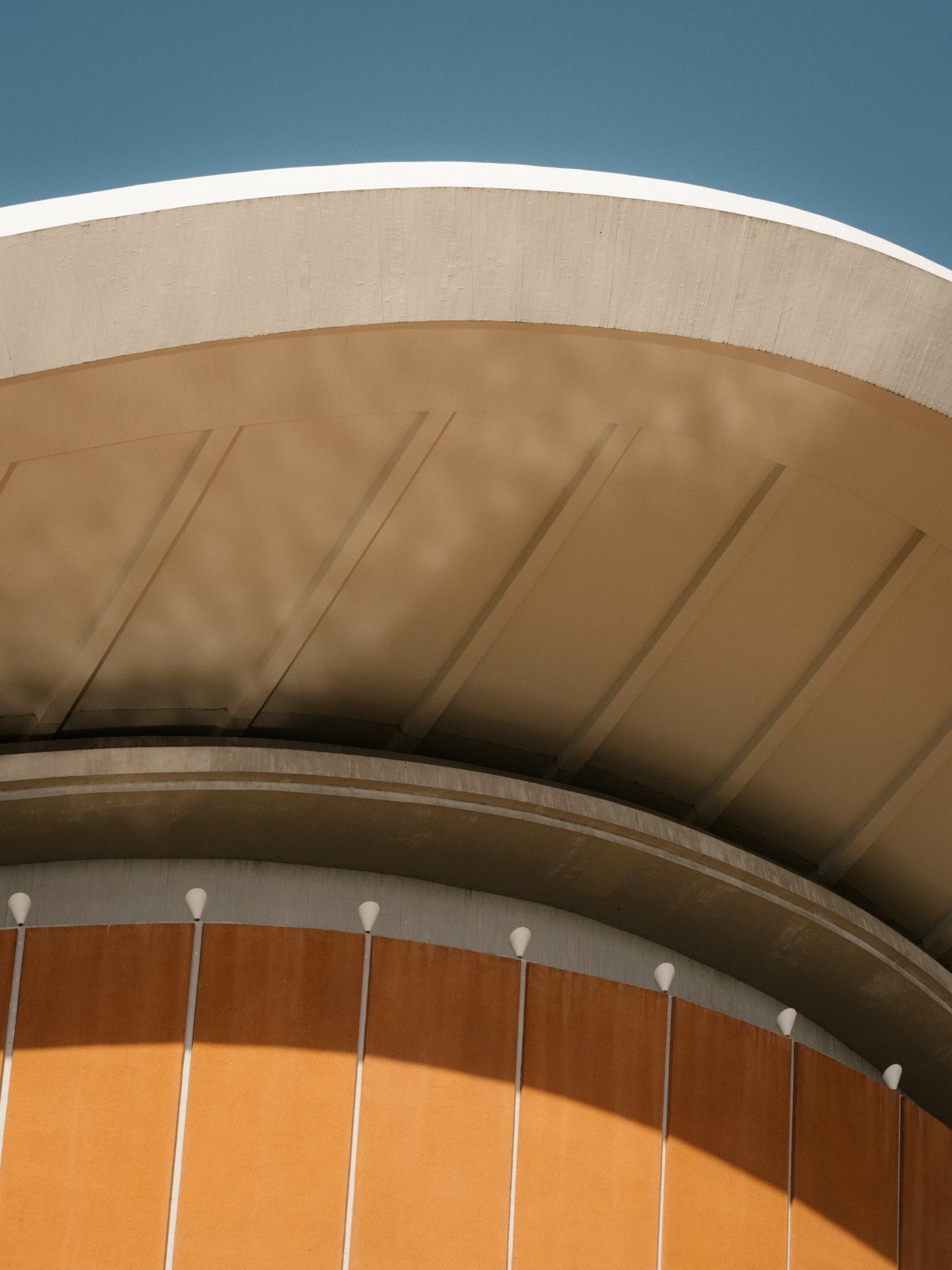 Berlin's Haus der Kulturen der Welt captured by Nate Cook by Hugh Stubbins — This close-up perspective isolates the Haus der Kulturen der Welt's distinctive curved vault, emphasizing its shell-like geometry against a clear blue sky.