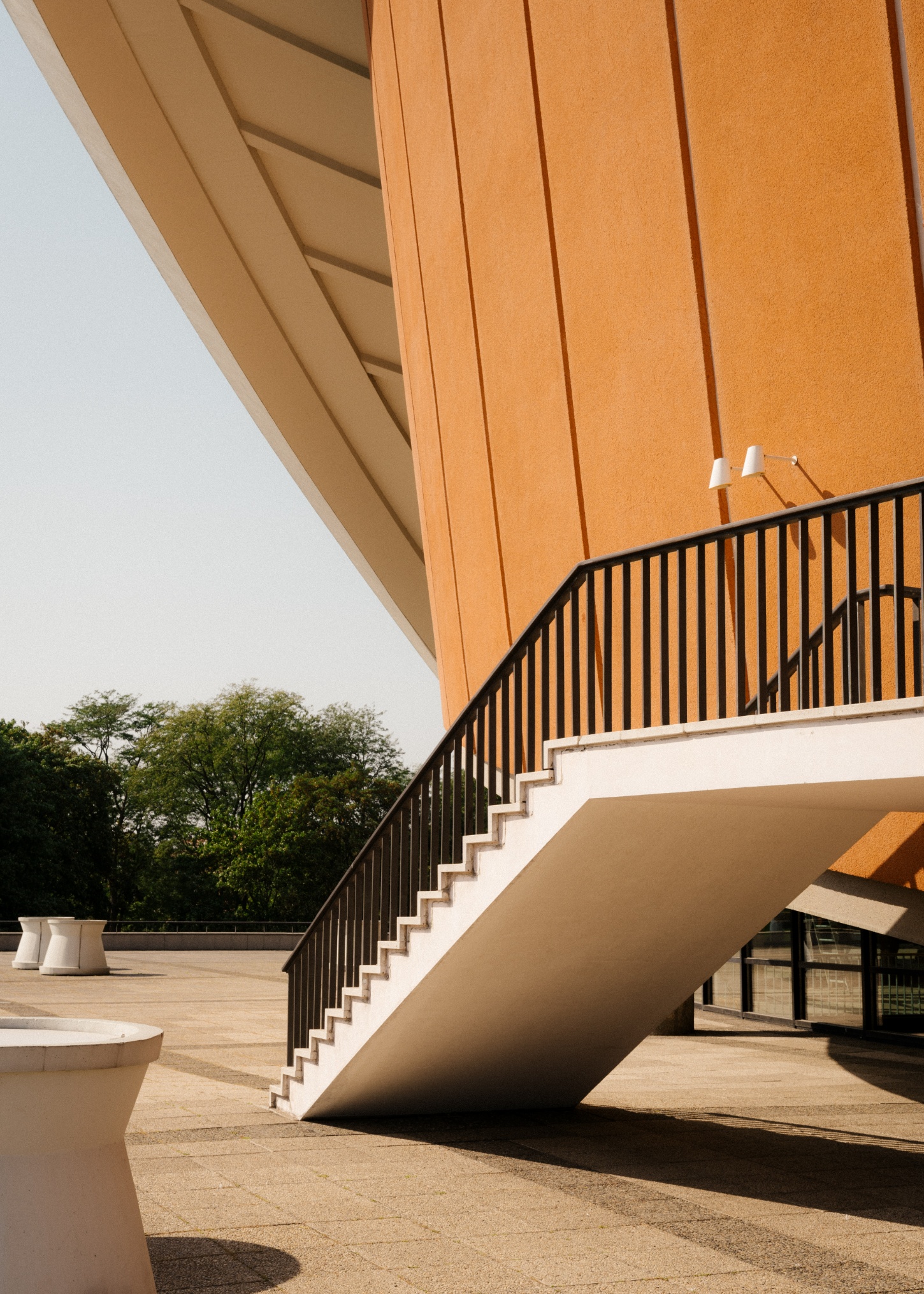 Berlin's Haus der Kulturen der Welt captured by Nate Cook by Hugh Stubbins — A monumental curved roof in warm terracotta dominates this terrace view, its shell-like form suspended between two structural points.