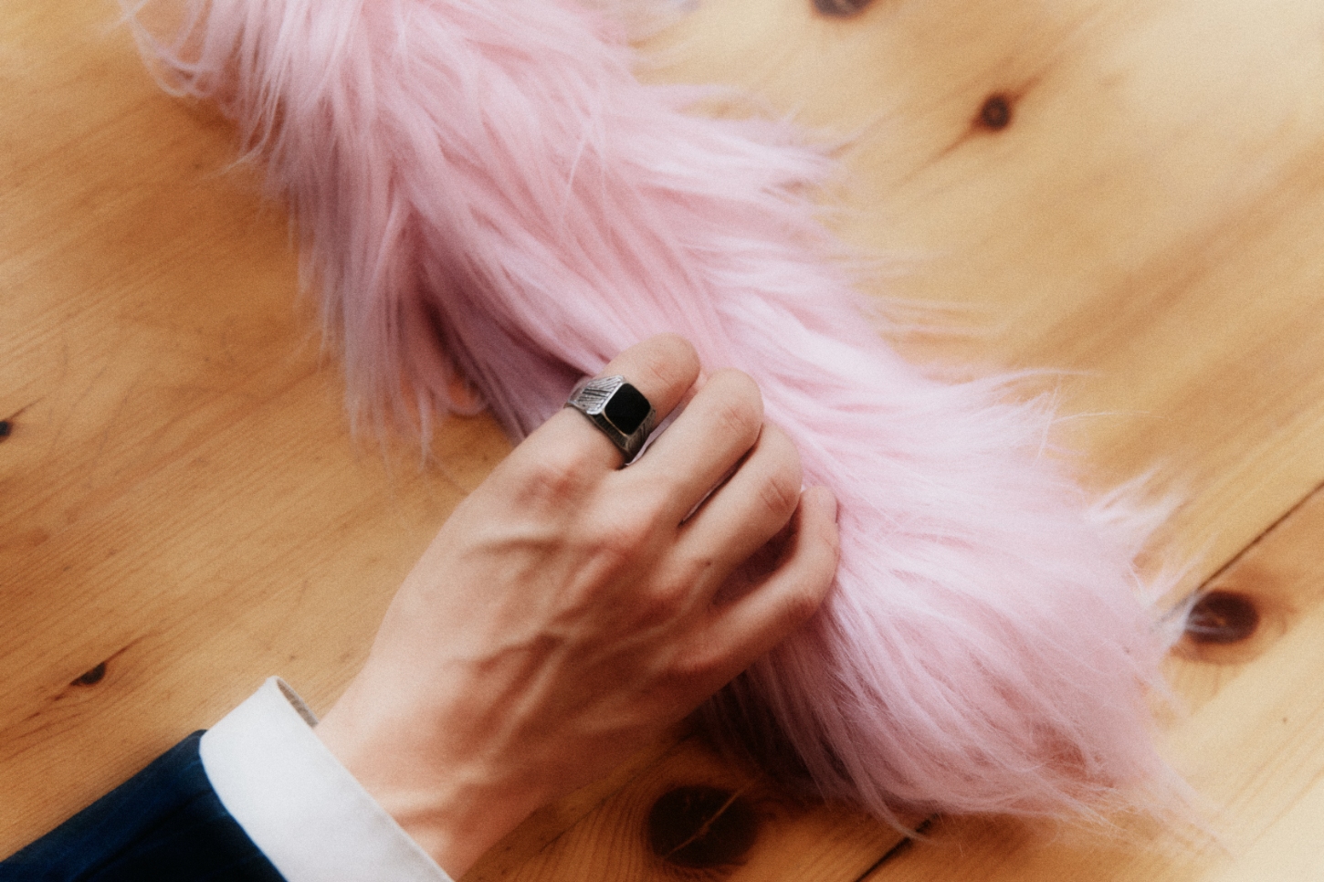 FURRY by Pedestal x NIKO JUNE — A close-up detail shot captures a hand resting on pink synthetic fur, revealing the tactile quality central to the FURRY cord sleeve design.