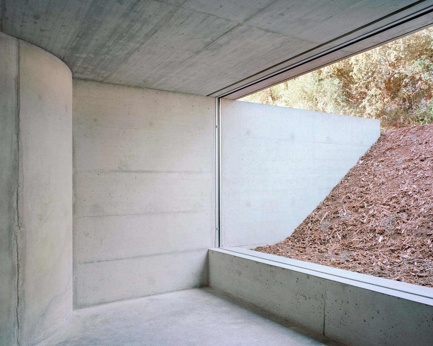 Tenant House by Arquitectura-G — A sunken interior space defined by board-formed concrete surfaces and continuous polished flooring.