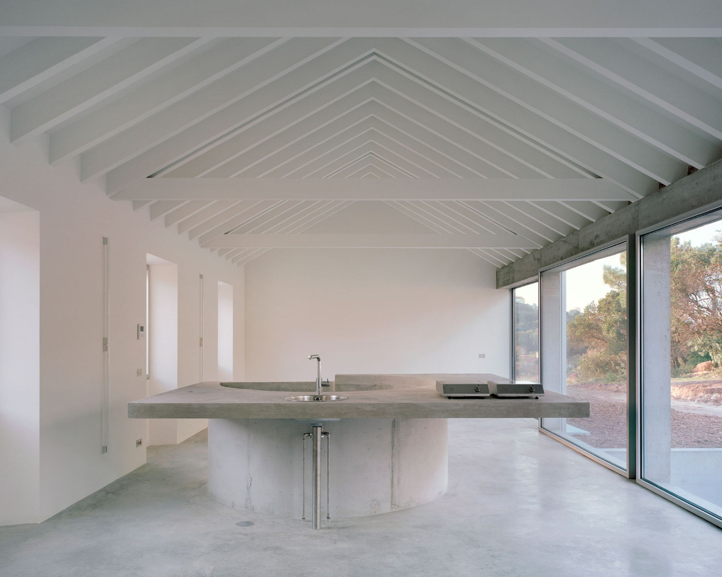 Tenant House by Arquitectura-G — A kitchen interior defined by massive concrete geometry and unobstructed landscape connection.
