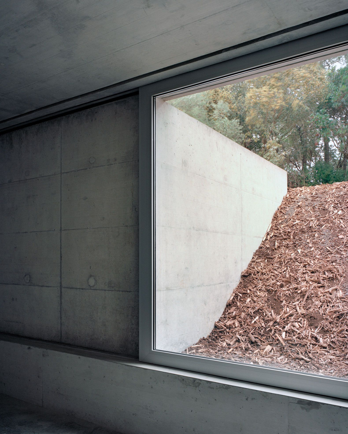Tenant House by Arquitectura-G — A sunken interior space defined by monolithic concrete construction and expansive glazing.