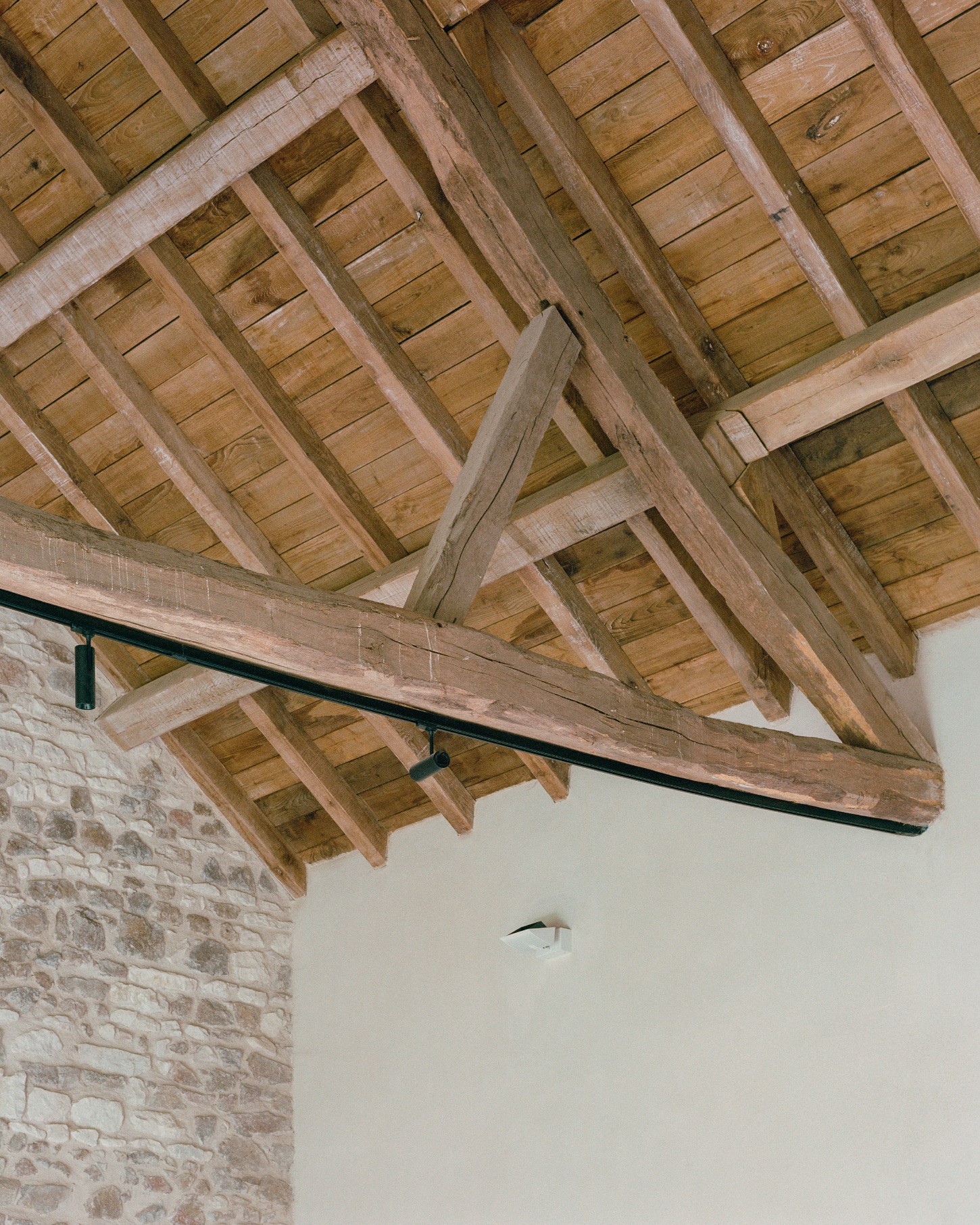Chamboirat by COVE Architectes — Overhead view of exposed timber roof structure revealing the barn's original post-and-beam framework.