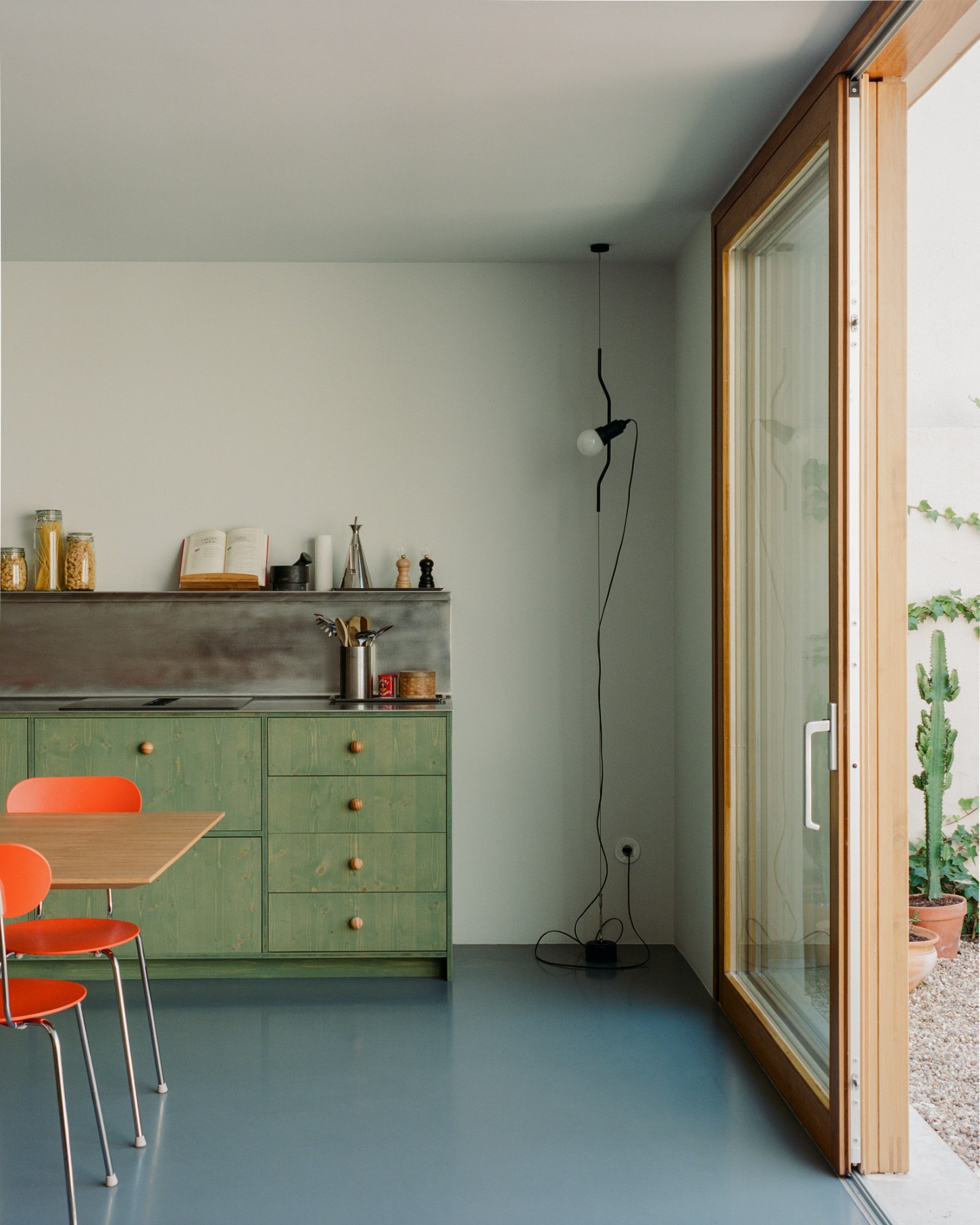 Marvilla House by Atelier José Andrade Rocha — A kitchen workspace anchors this pandemic-era renovation, where sage-green powder-coated steel cabinetry with timber-framed pulls establishes the primary...