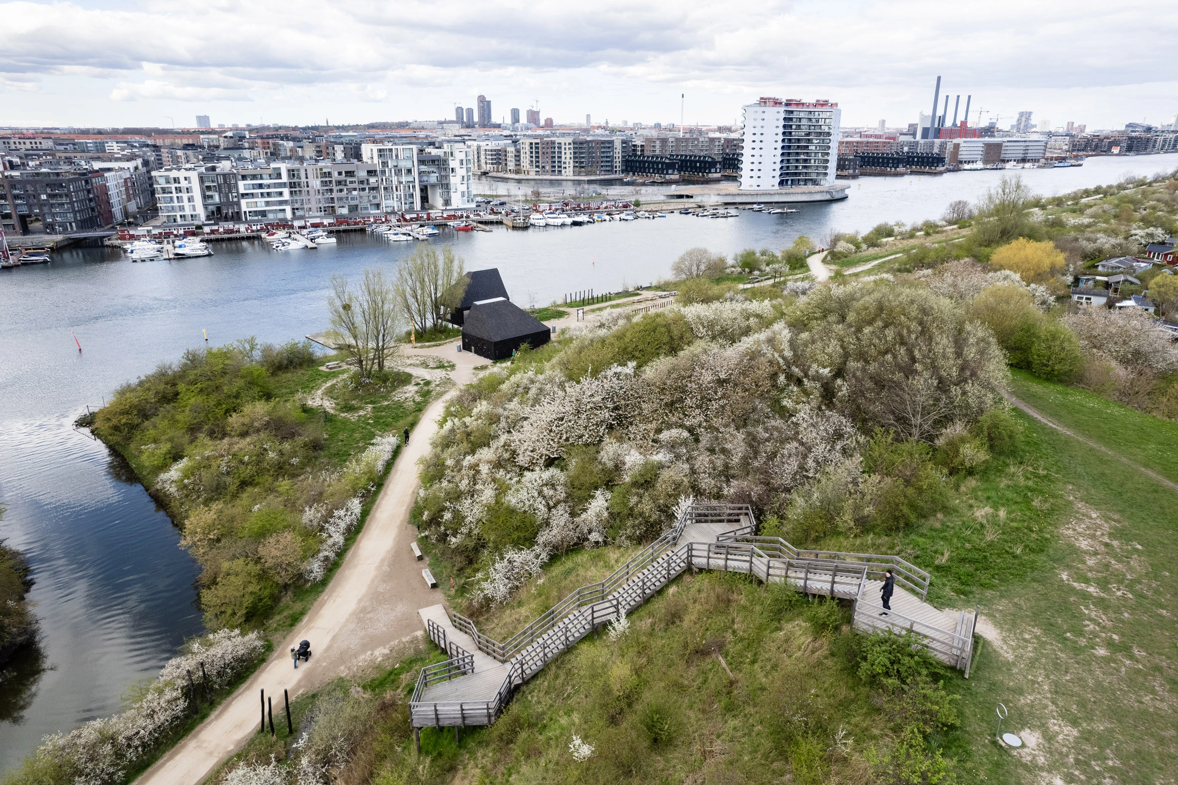 Amager Nature Park by ADEPT and LYTT Architecture — Aerial view of Amager Nature Park's visitor pavilion situated on sloped terrain overlooking Copenhagen's waterfront.
