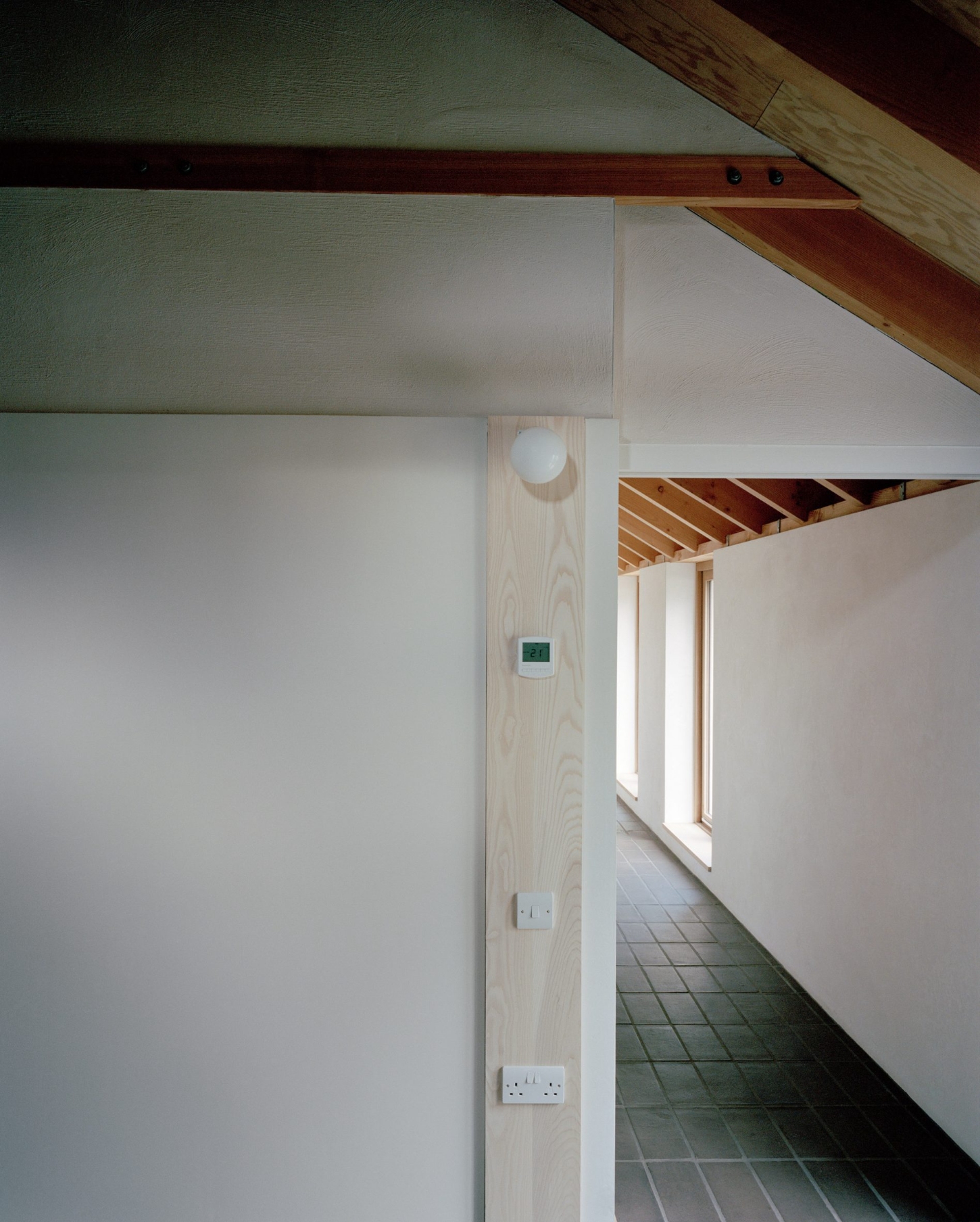 Farmworker's House by Hugh Strange Architects — Interior passage with exposed timber roof structure and light-colored rendered walls.