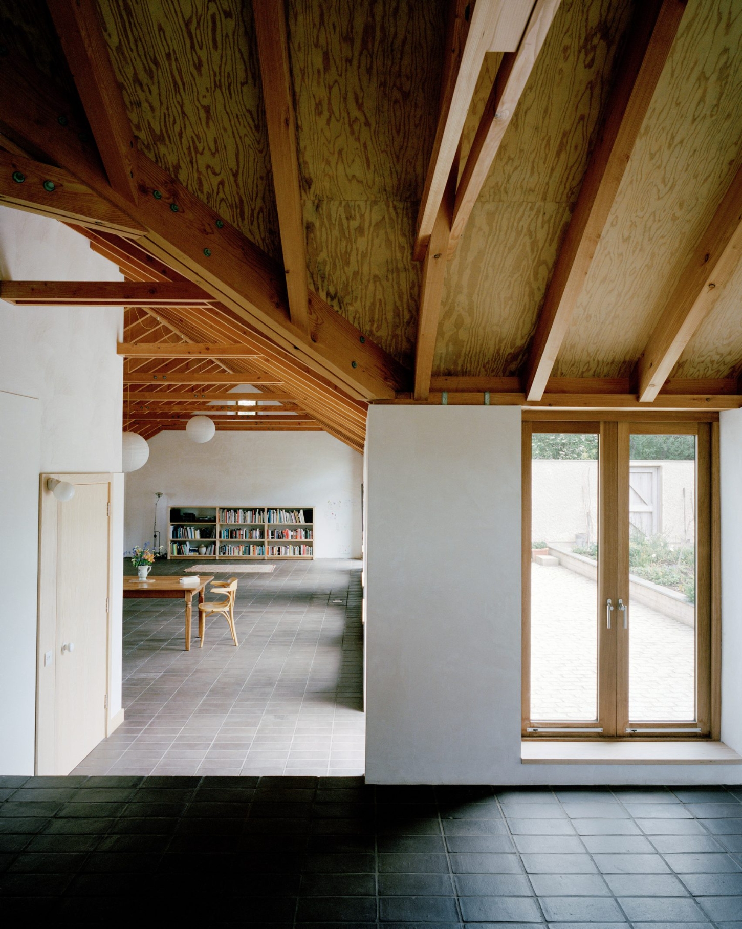 Farmworker's House by Hugh Strange Architects — This interior view captures the open-plan living space with exposed timber roof structure and plywood soffit panels overhead.