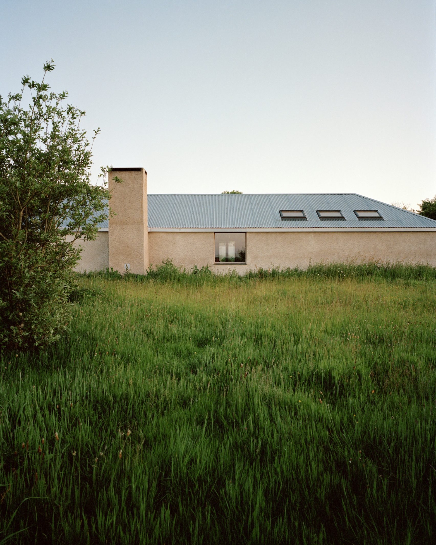 Farmworker's House by Hugh Strange Architects — The Farmworker's House reveals itself as a low, horizontal volume anchored within tall meadow grasses.