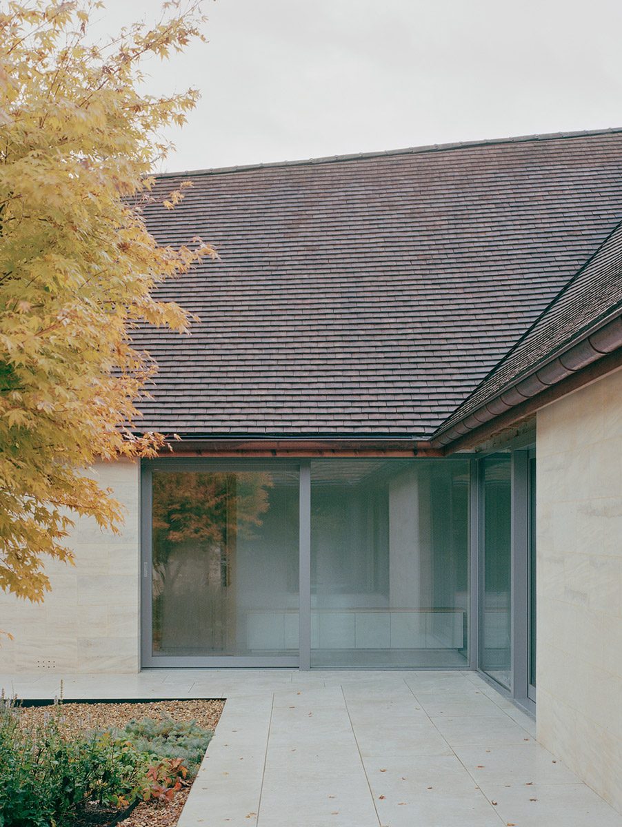 Eavesdrop by Tom Dowdall — The southeast-facing elevation of Eavesdrop presents a continuous band of horizontal glazing set within rendered white walls, framed by a pitched slate roof...