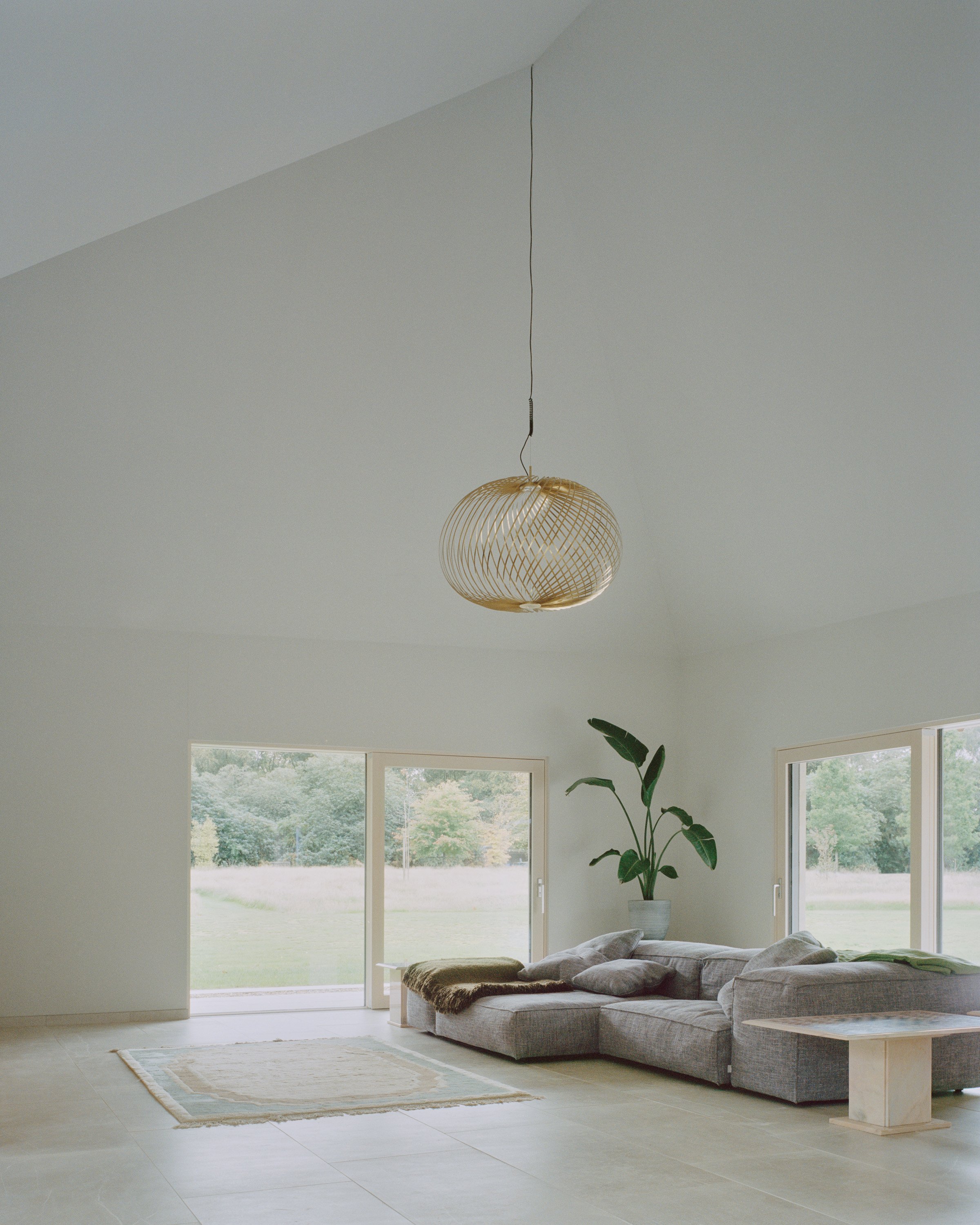 Eavesdrop by Tom Dowdall — A single-story interior bathed in diffused daylight from expansive glazed doors framing woodland views.