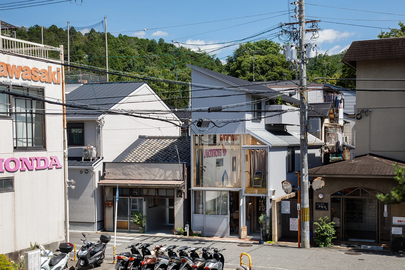 House A/Shop B (Bolts Hardware Store) by KimuraMatsumoto Architects — Daytime street view of the narrow infill structure wedged between neighboring buildings.