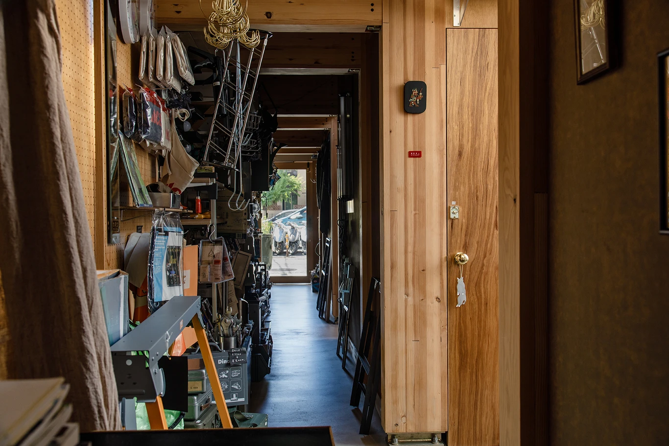 House A/Shop B (Bolts Hardware Store) by KimuraMatsumoto Architects — A narrow timber-lined corridor extends toward the storefront, revealing the compressed spatial strategy of House A/Shop B.