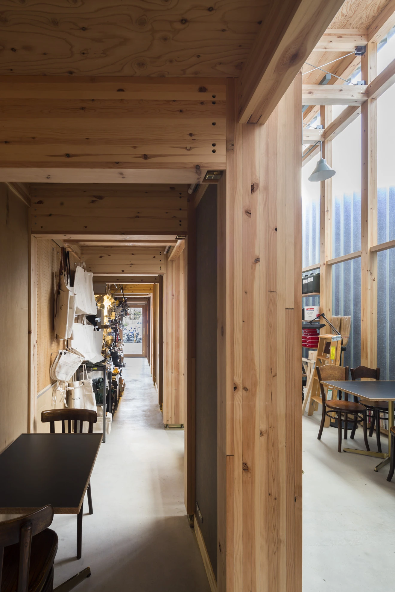 House A/Shop B (Bolts Hardware Store) by KimuraMatsumoto Architects — A recessed corridor framed by timber post-and-beam construction reveals the depth of House A/Shop B's narrow footprint.