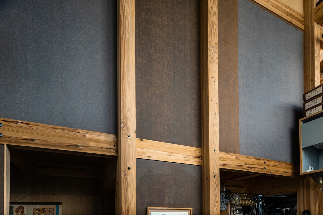 House A/Shop B (Bolts Hardware Store) by KimuraMatsumoto Architects — Interior view of the hardware store's upper level reveals the structural post-and-beam framework in pine timber dividing the space into distinct sections.
