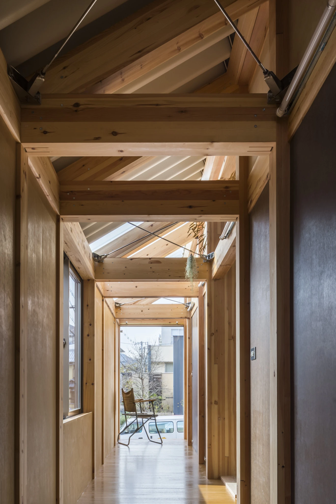 House A/Shop B (Bolts Hardware Store) by KimuraMatsumoto Architects — A receding corridor lined with timber-framed structural elements creates a deep perspective through the building's narrow footprint.
