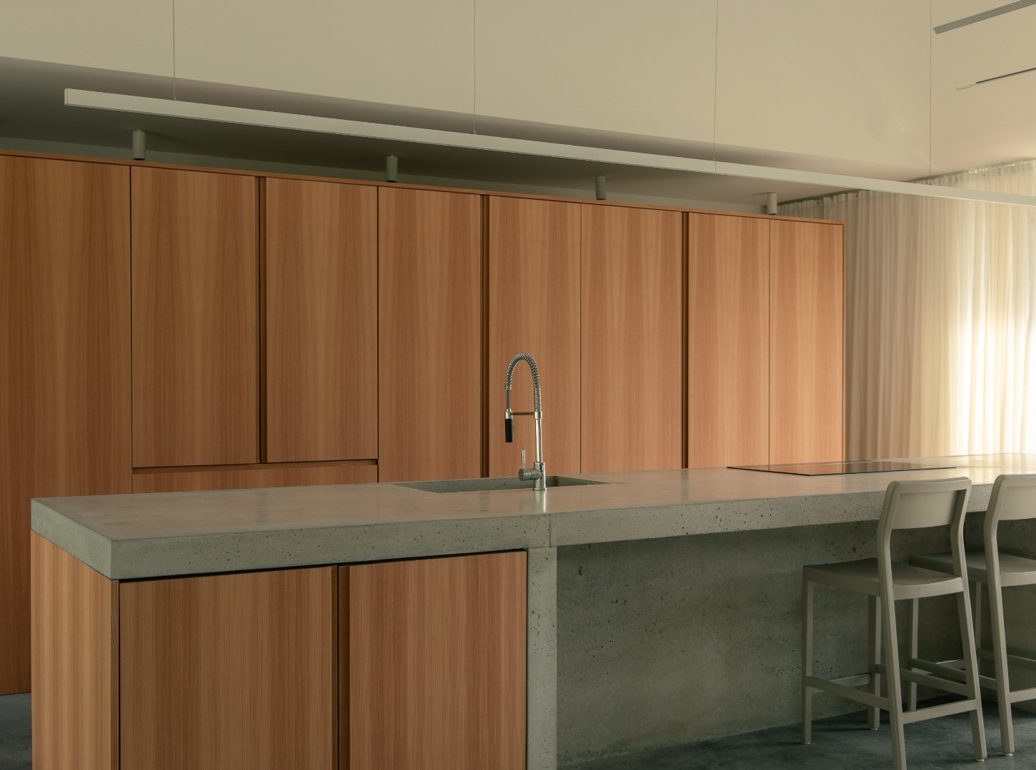 House in a Meadow by Group Projects Architecture — Interior view of the kitchen island with concrete countertop featuring aggregate visible throughout its surface.